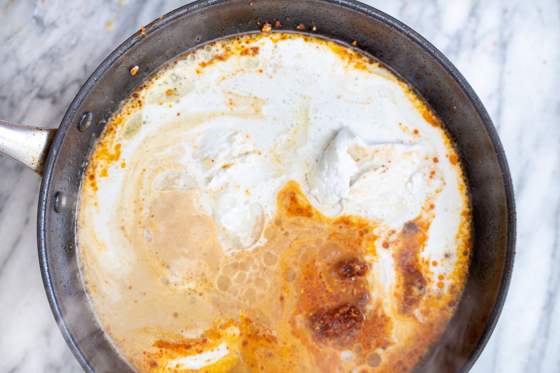 coconut milk being added to thai curry in a saucepan