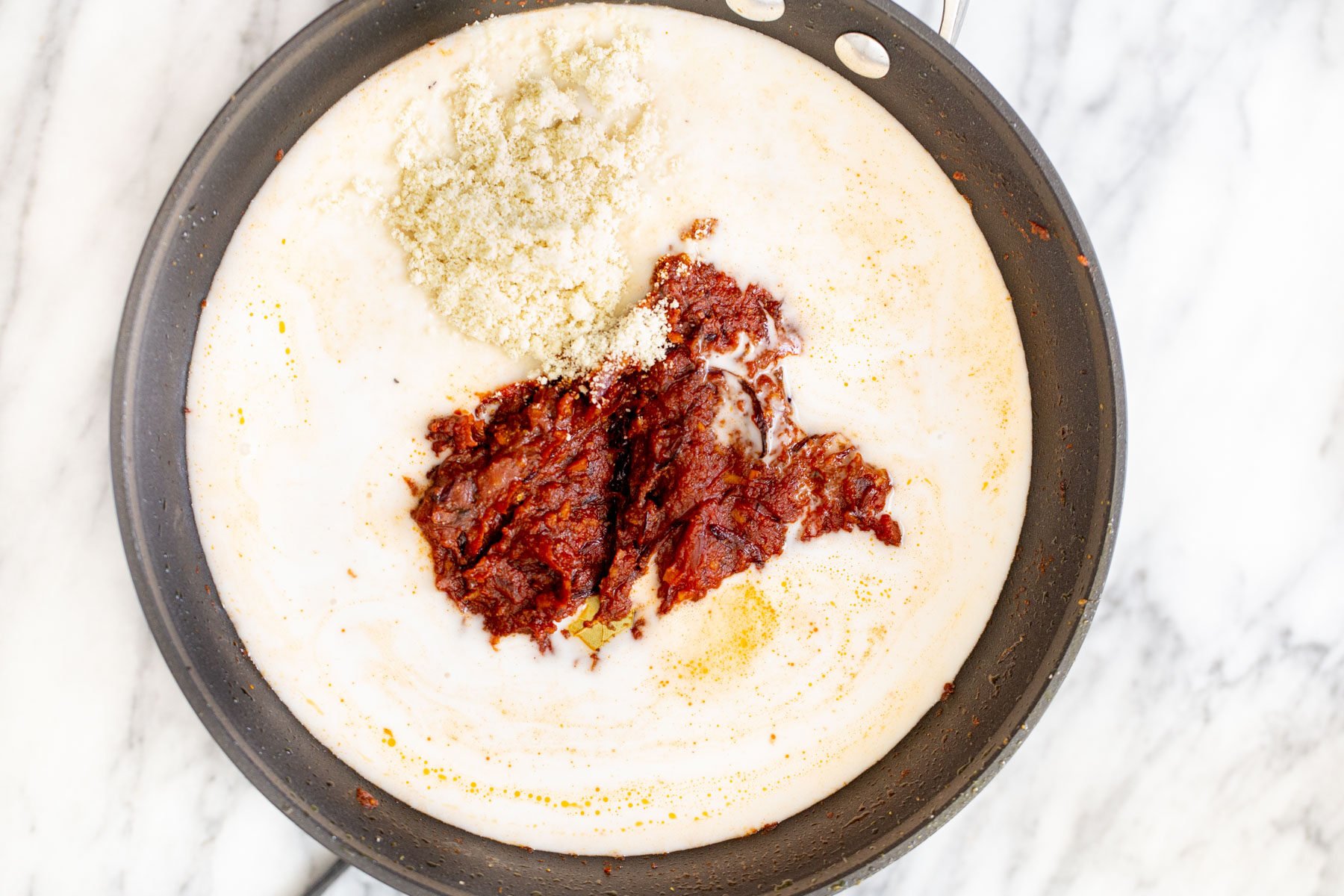 coconut milk, tomato paste and spice mix in a black frying pan