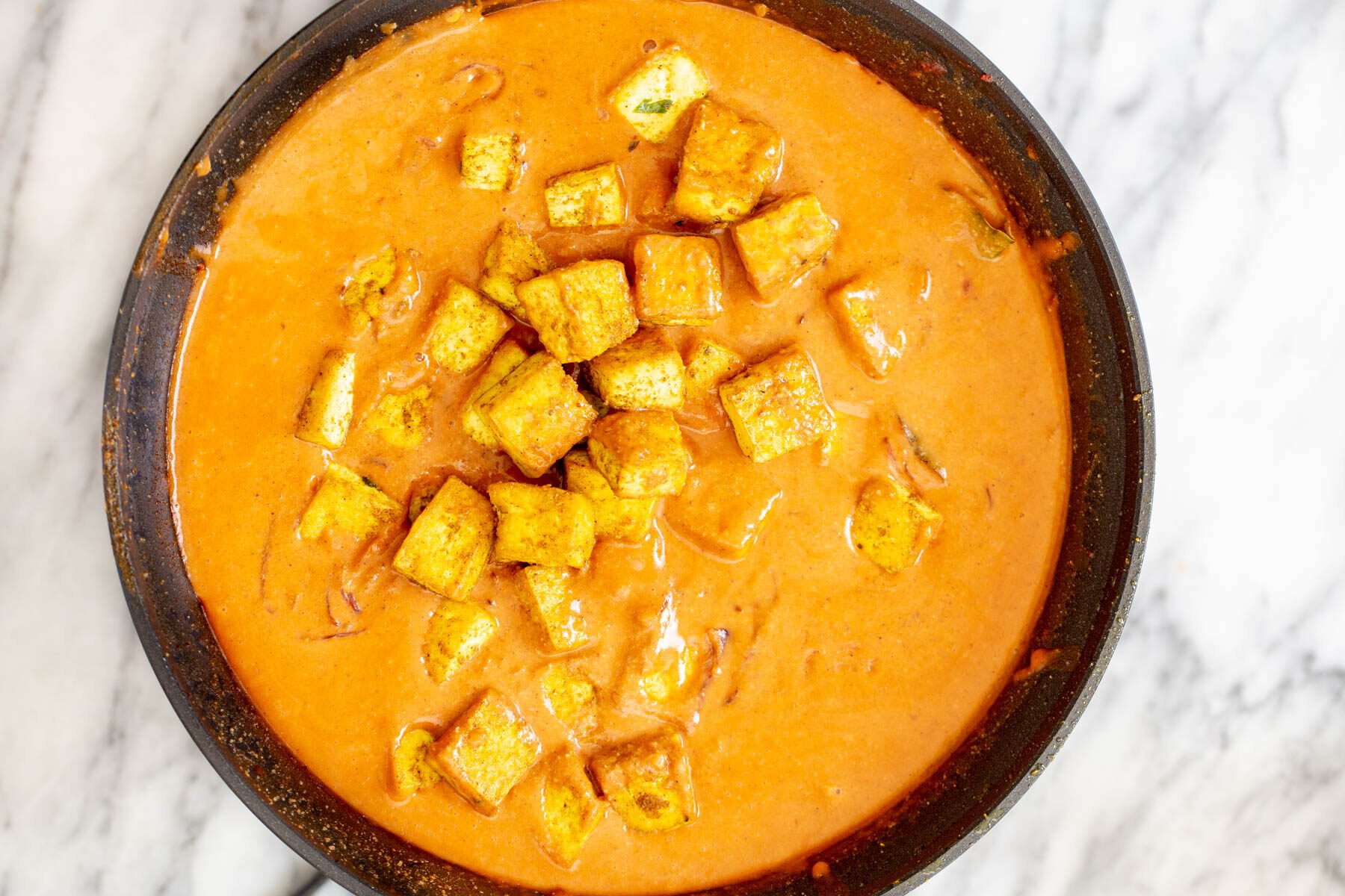 tofu malai pan-fried tofu cubes in a black frying pan