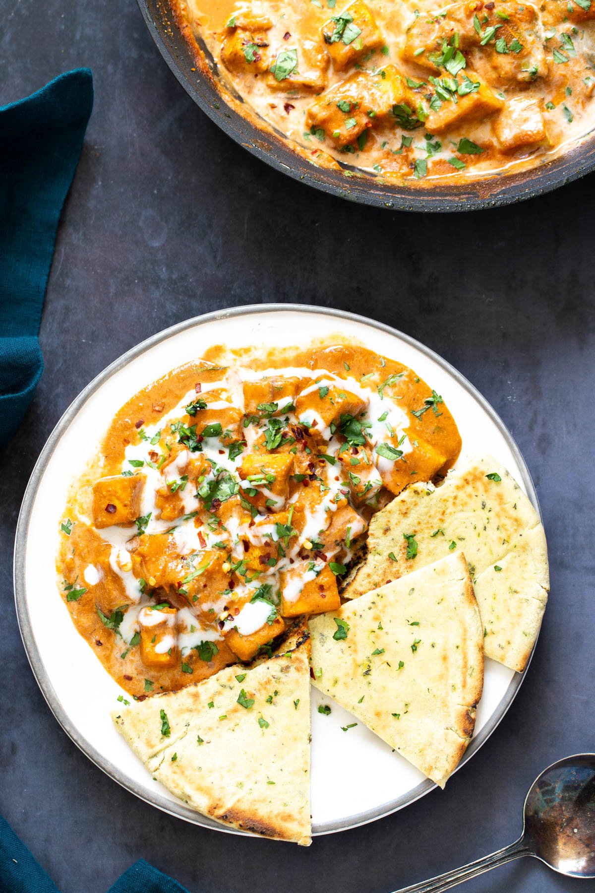 overhead shot of a serving of malai tofu curry served with a side of quartered naan