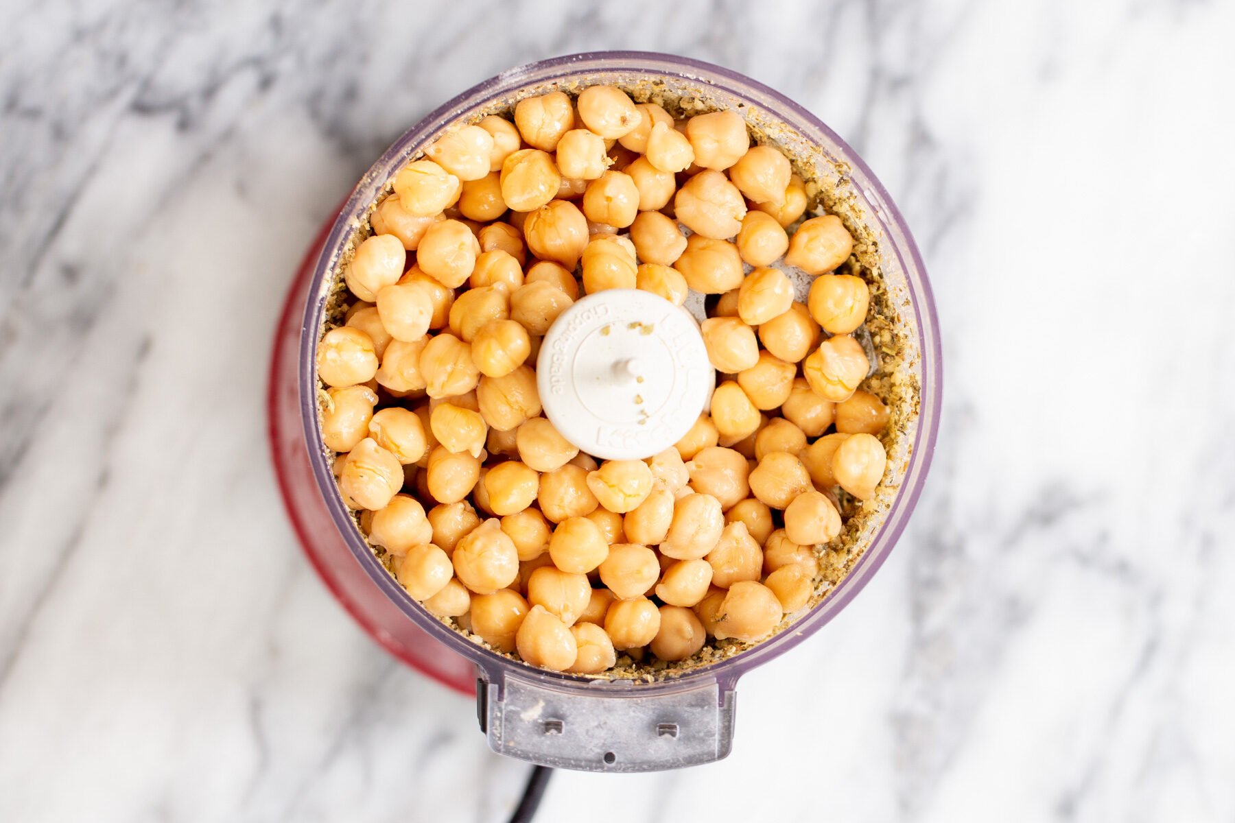 chickpeas being added to a food processor to make vegan stuffing