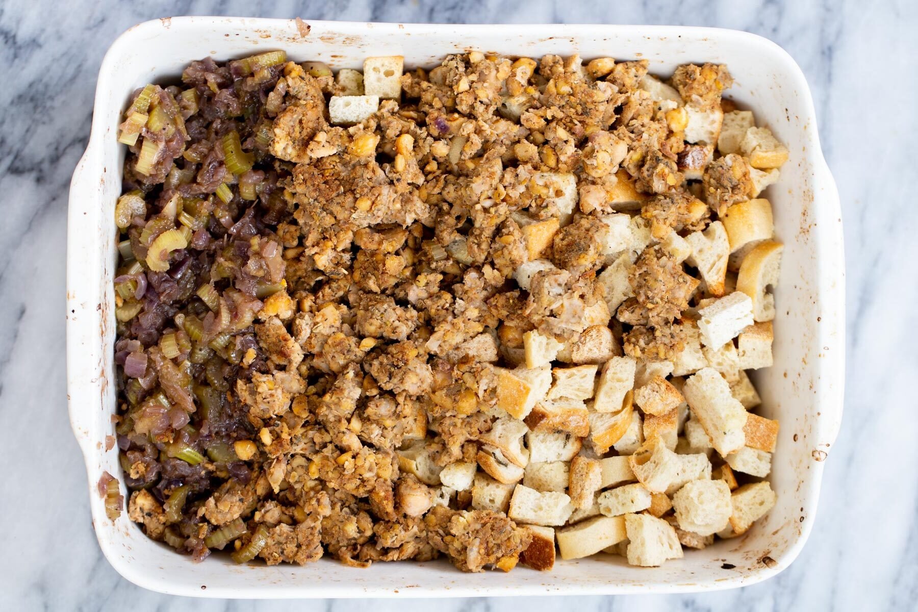 vegan stuffing vegan stuffing being tossed in a white casserole dish