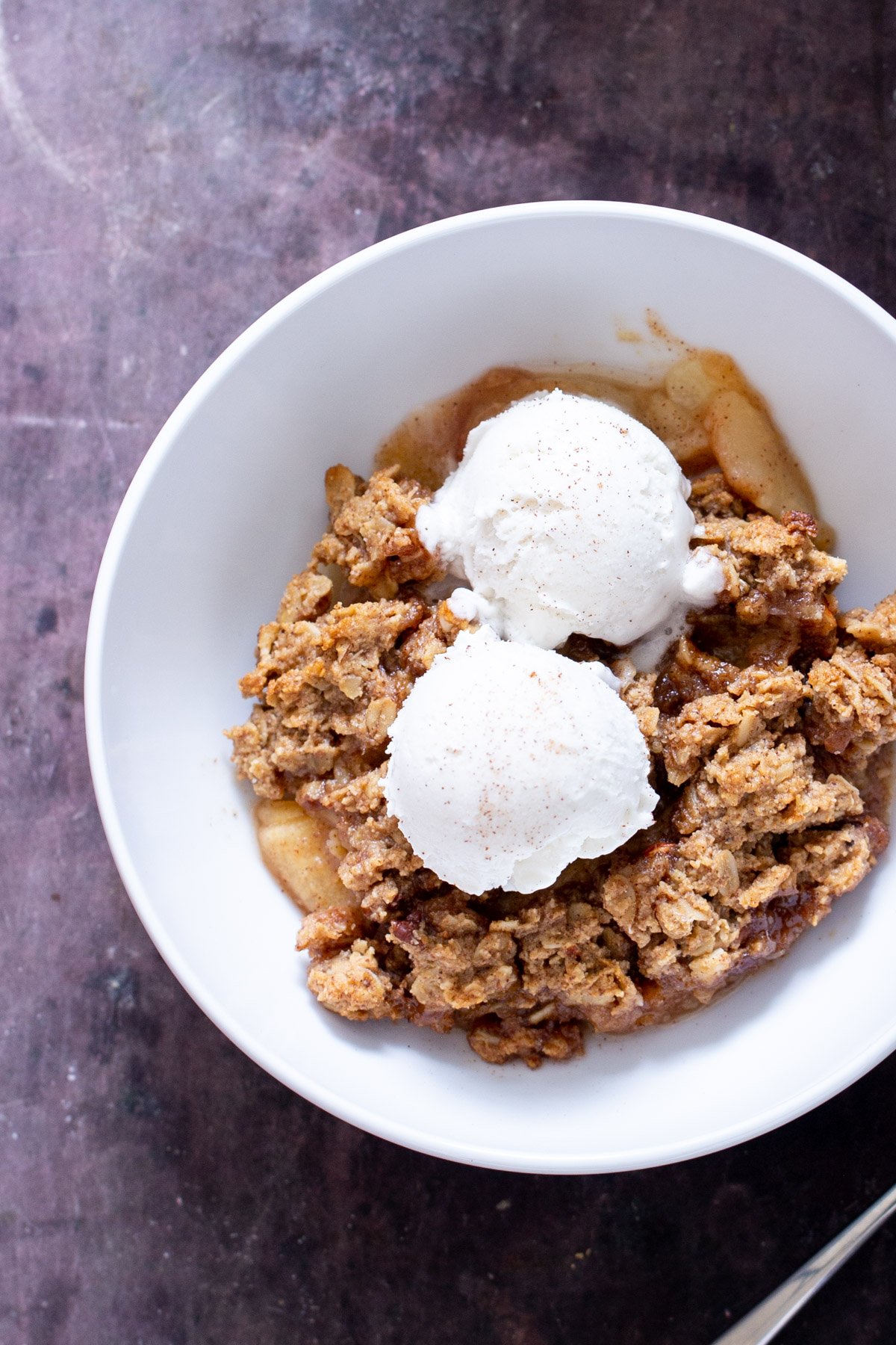 a plate with vegan glutenfree apple pear crisp topped with vanilla ice cream