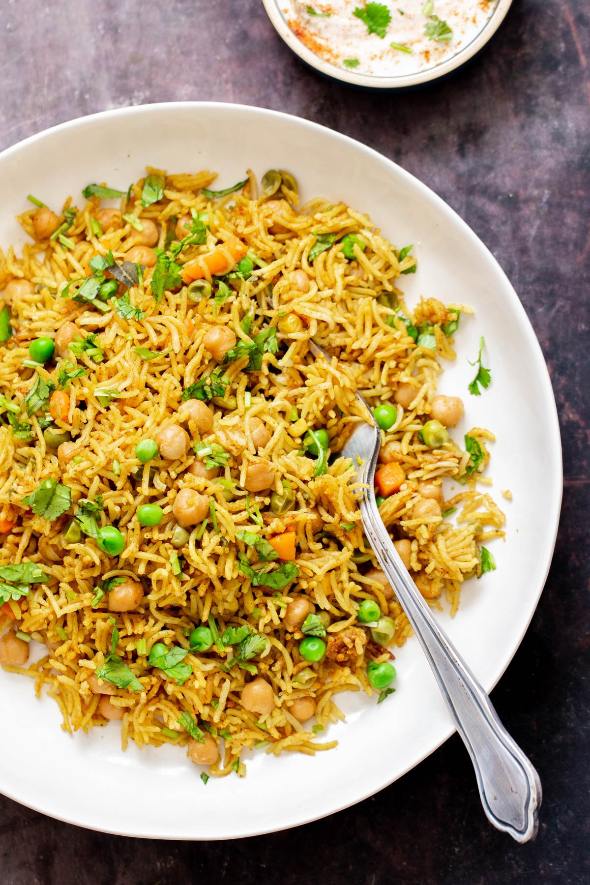 chickpea fried rice a plate of Instant Pot Curried Chickpea Fried Rice with peas served with a silver spoon