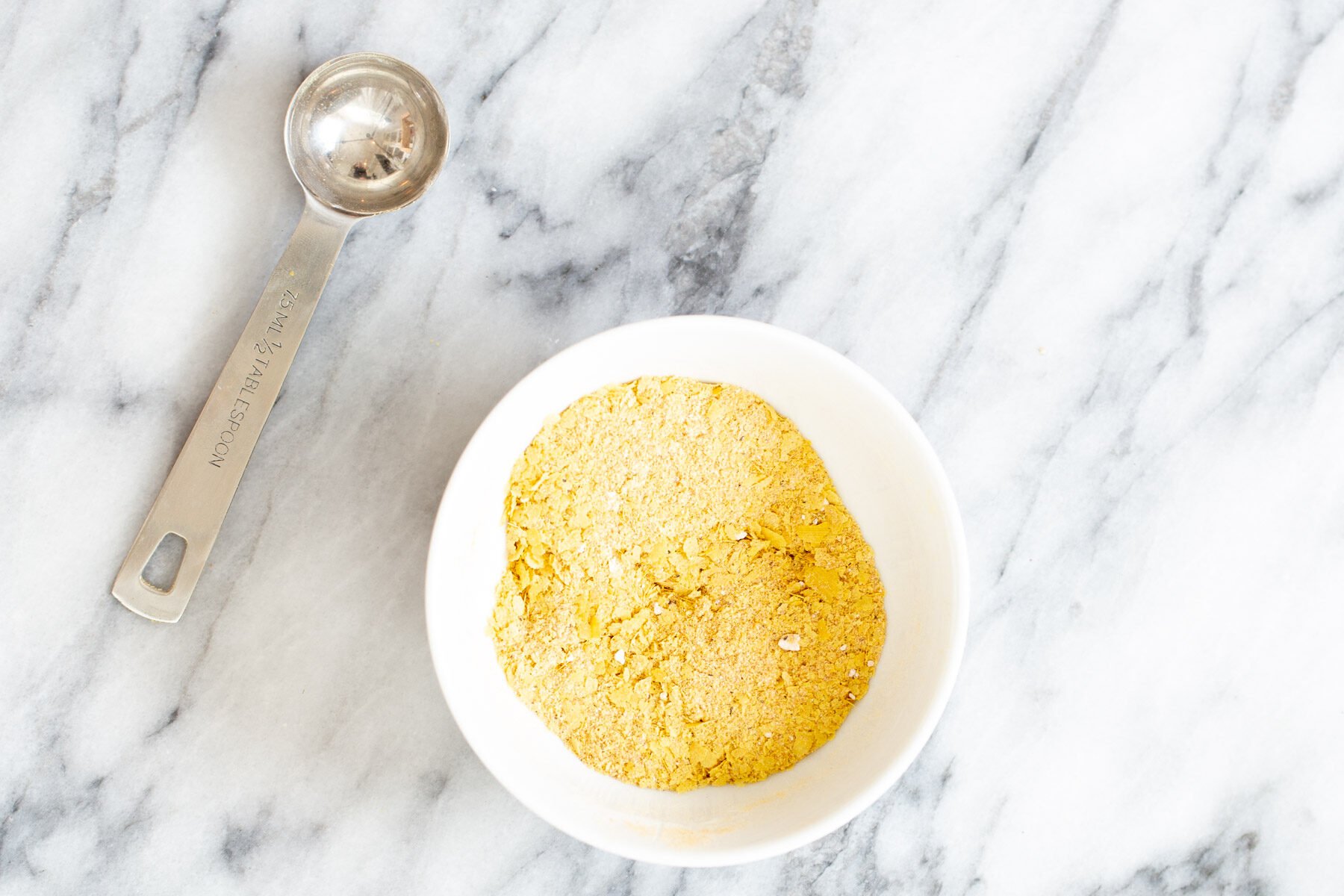 vegan tofu scramble seasoning in a white bowl with a measuring spoon on the side