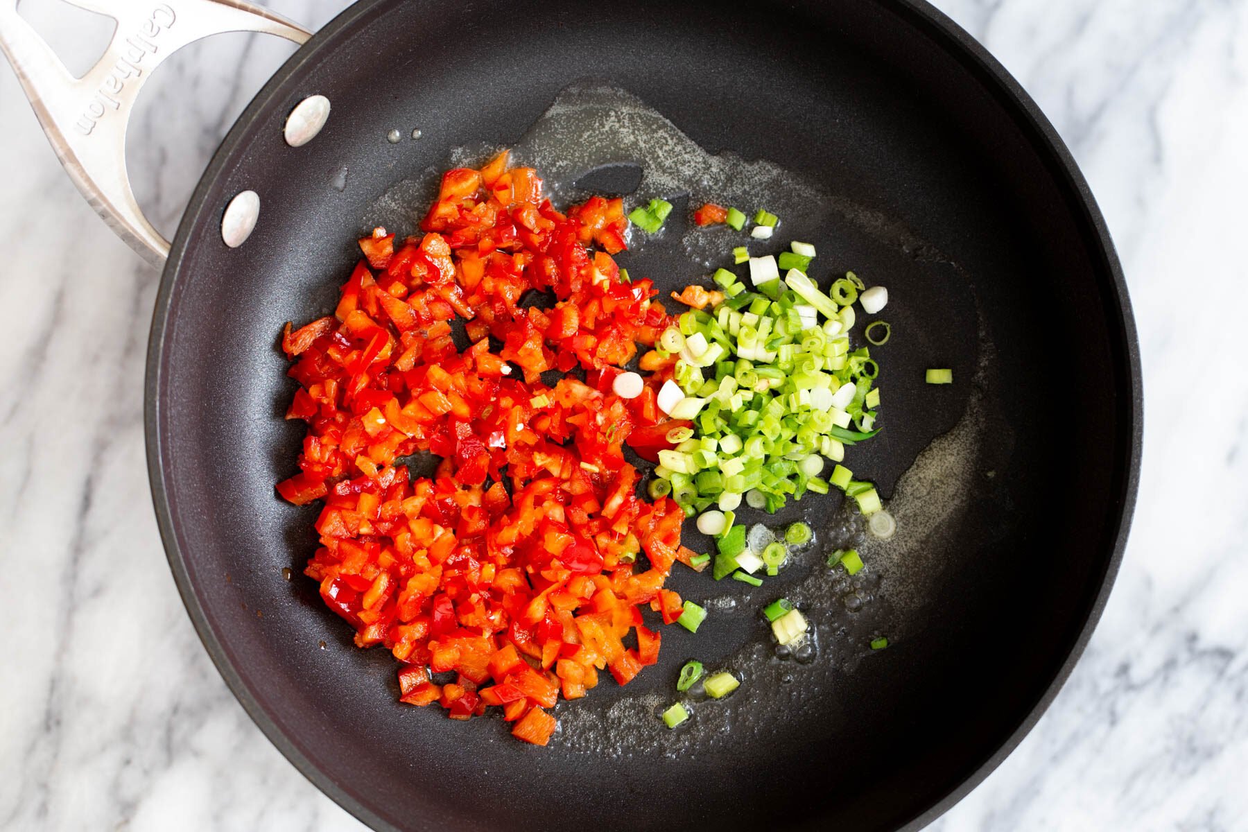 tofu scramble seasoning  bell pepper and green onions in a sauteeing pan