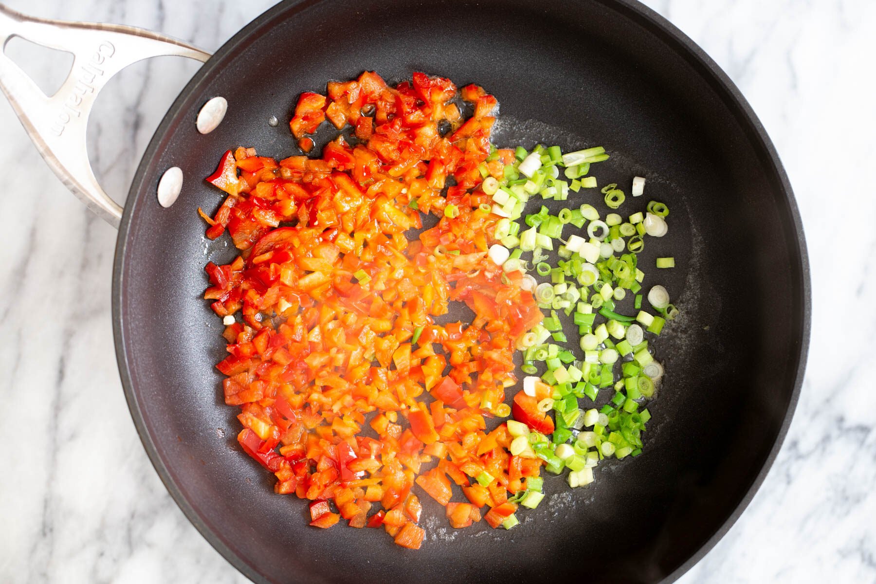 red bell pepper and green onions in a black skillet