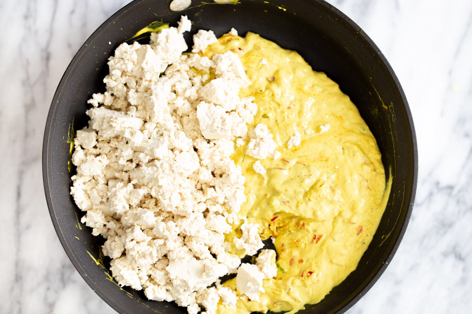 crumbled tofu being added to a pan to make tofu scramble