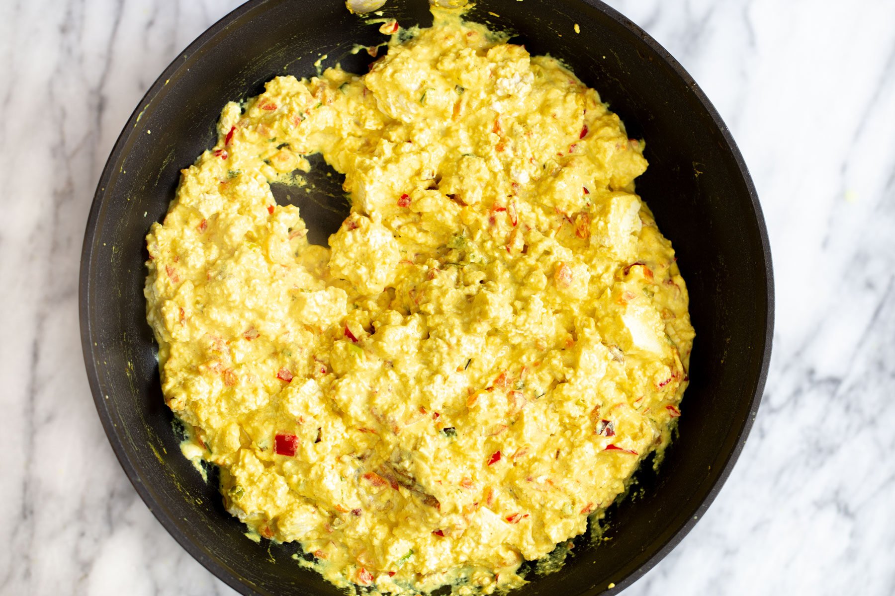 tofu scramble seasoning  vegan tofu scramble being prepared in a black skillet