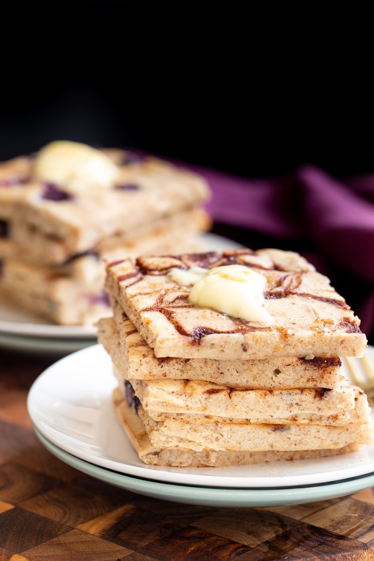 vegan cinnamon swirl sheet pan pancakes stacked on a white plate