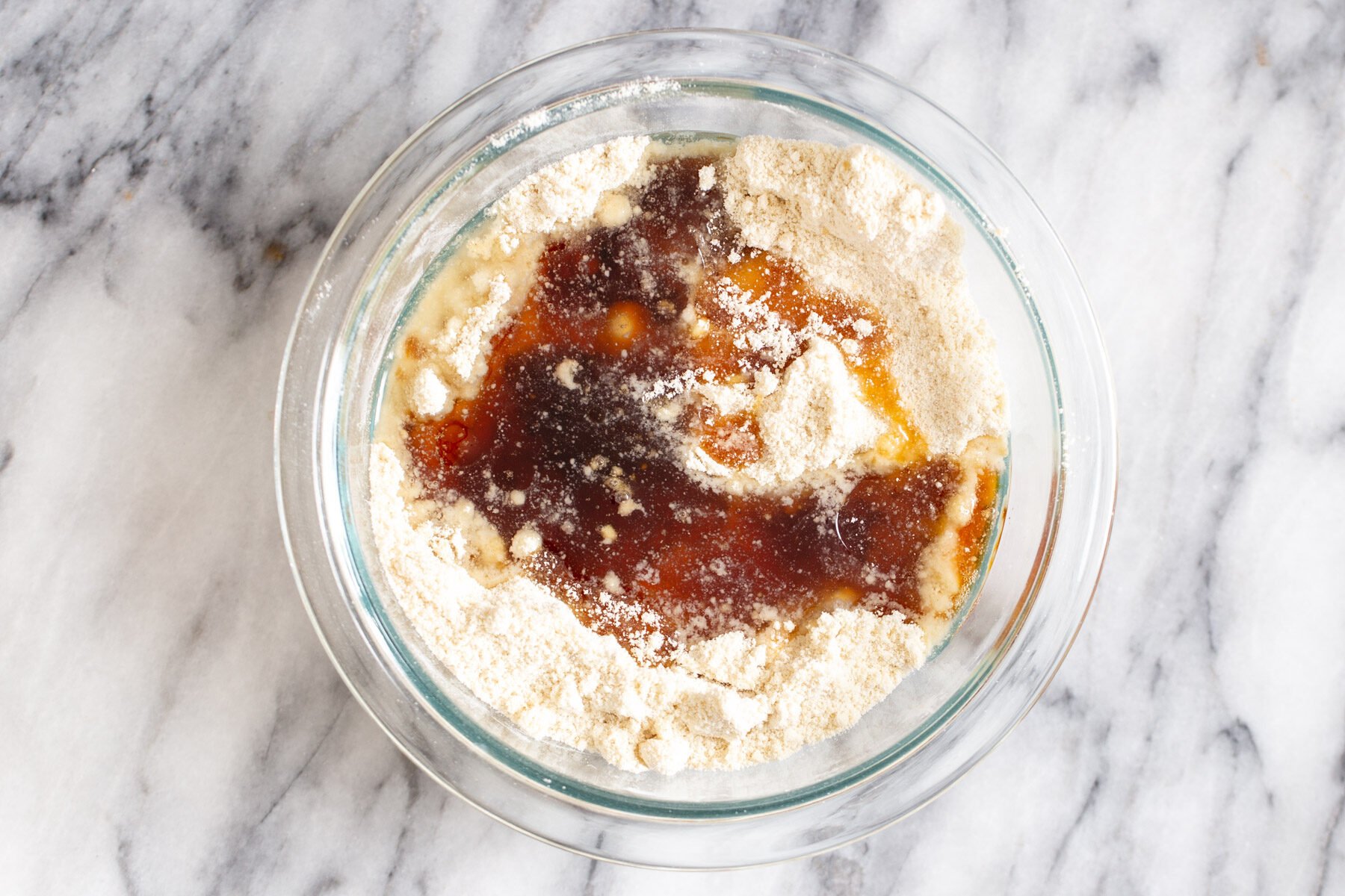 gluten free thumbprint cookies wet ingredients being added to dry ingredients in a glass bowl