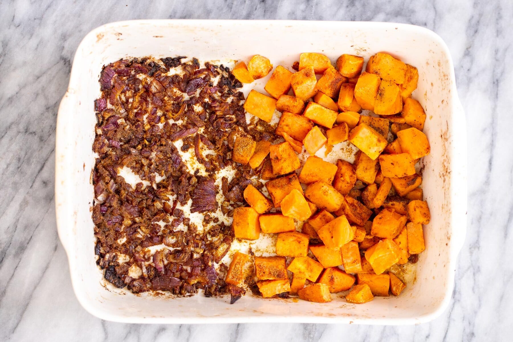 baked sweet potato cubes and onion in a casserole dish