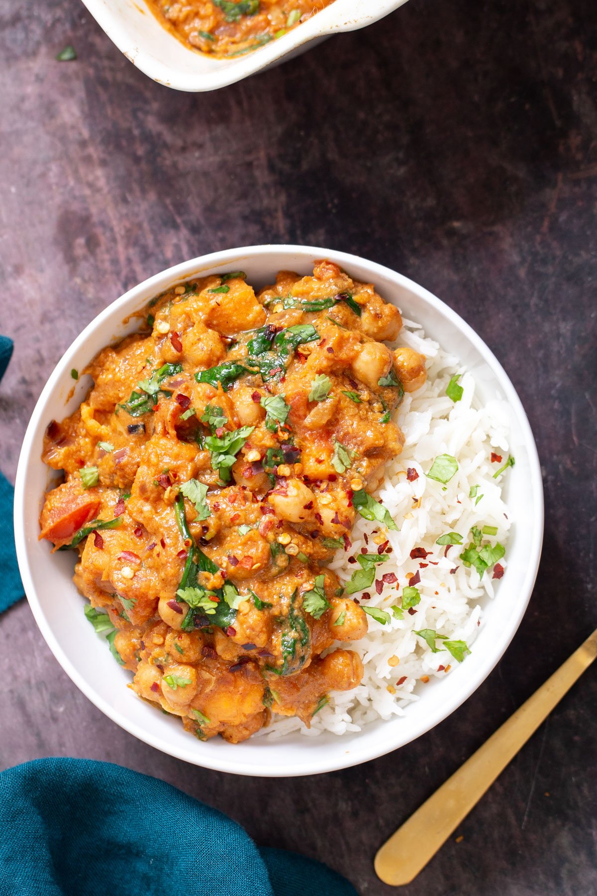 a serving of vegan baked sweet potato chickpea curry served with rice sprinkled with cilantro