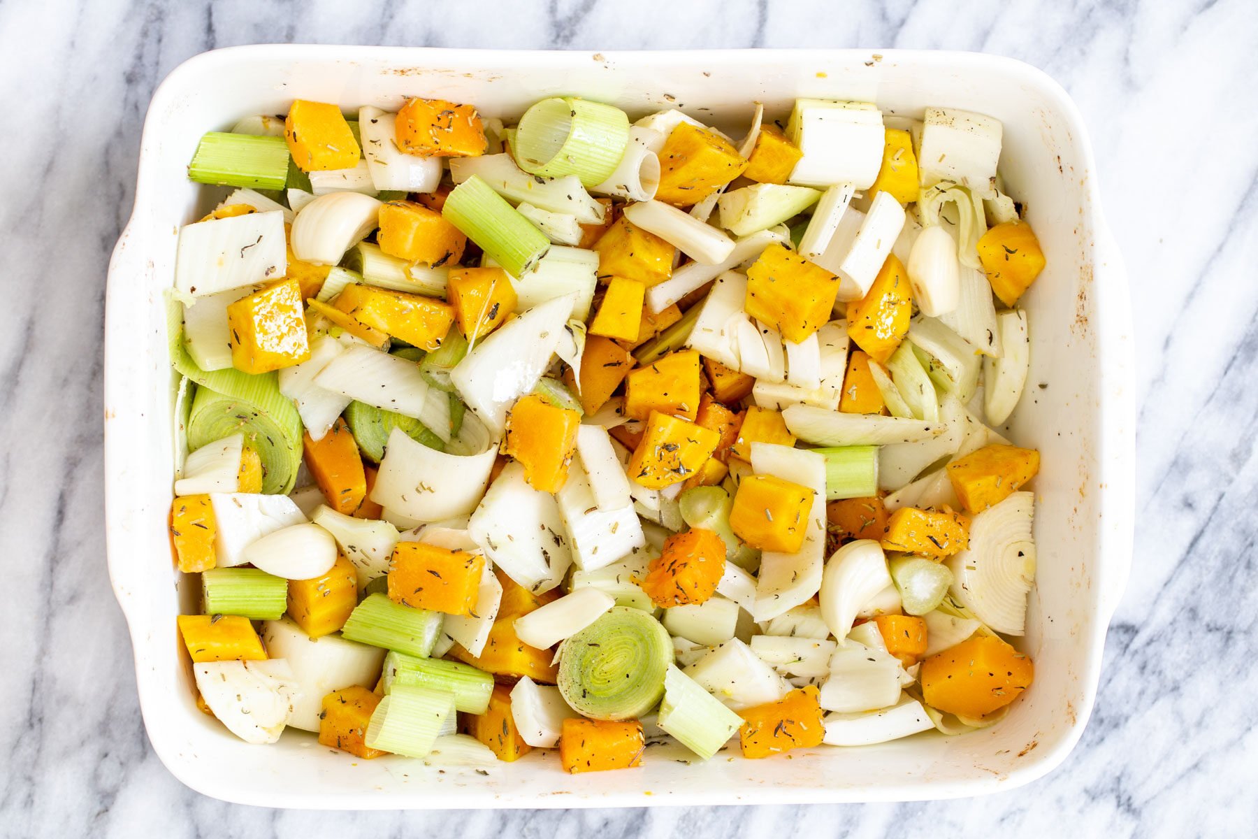 roasted root vegetables tossed with seasoning in a casserole dish