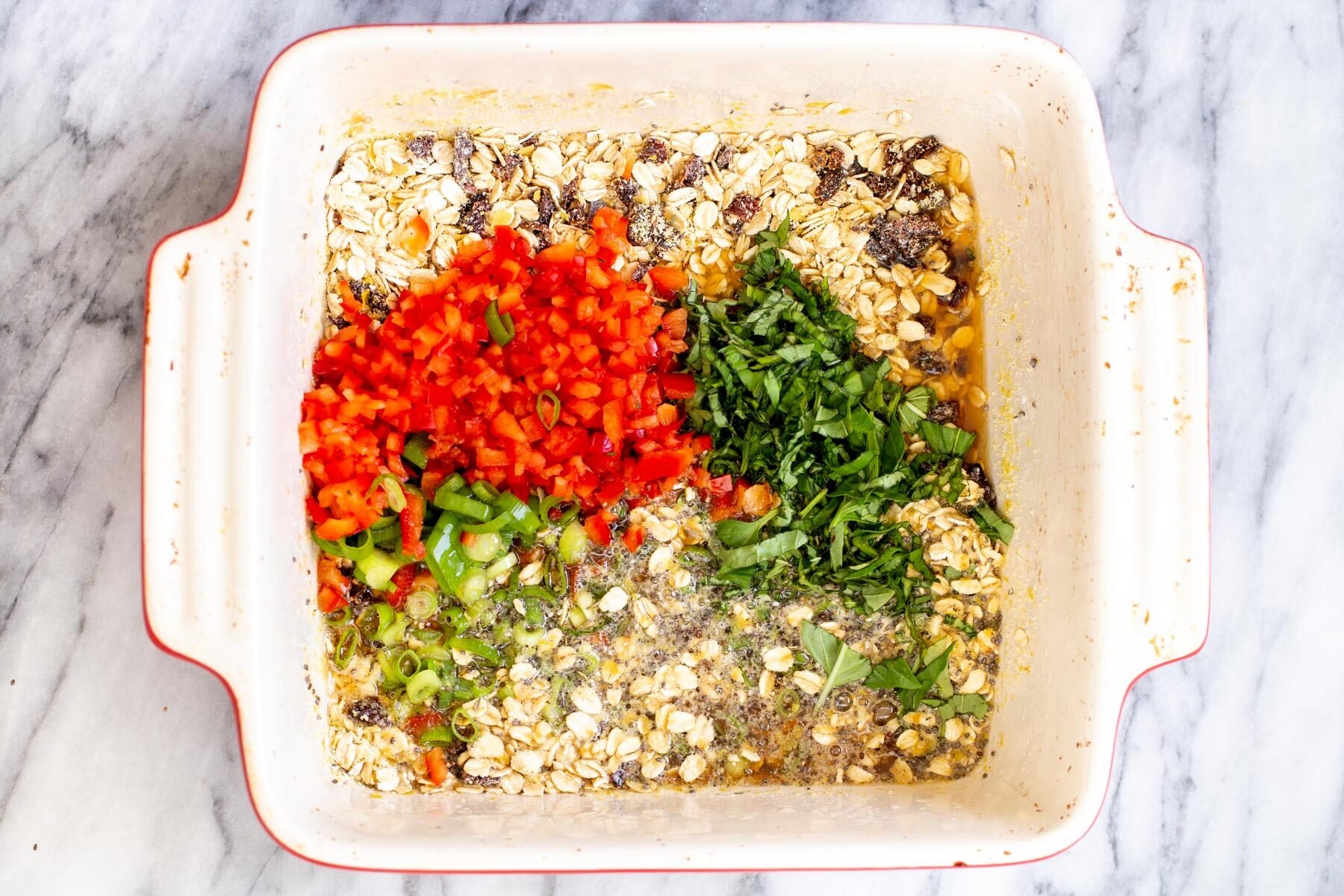 savory oatmeal bake  bell peppers and spring onions being added to dry ingredients in a casserole dish