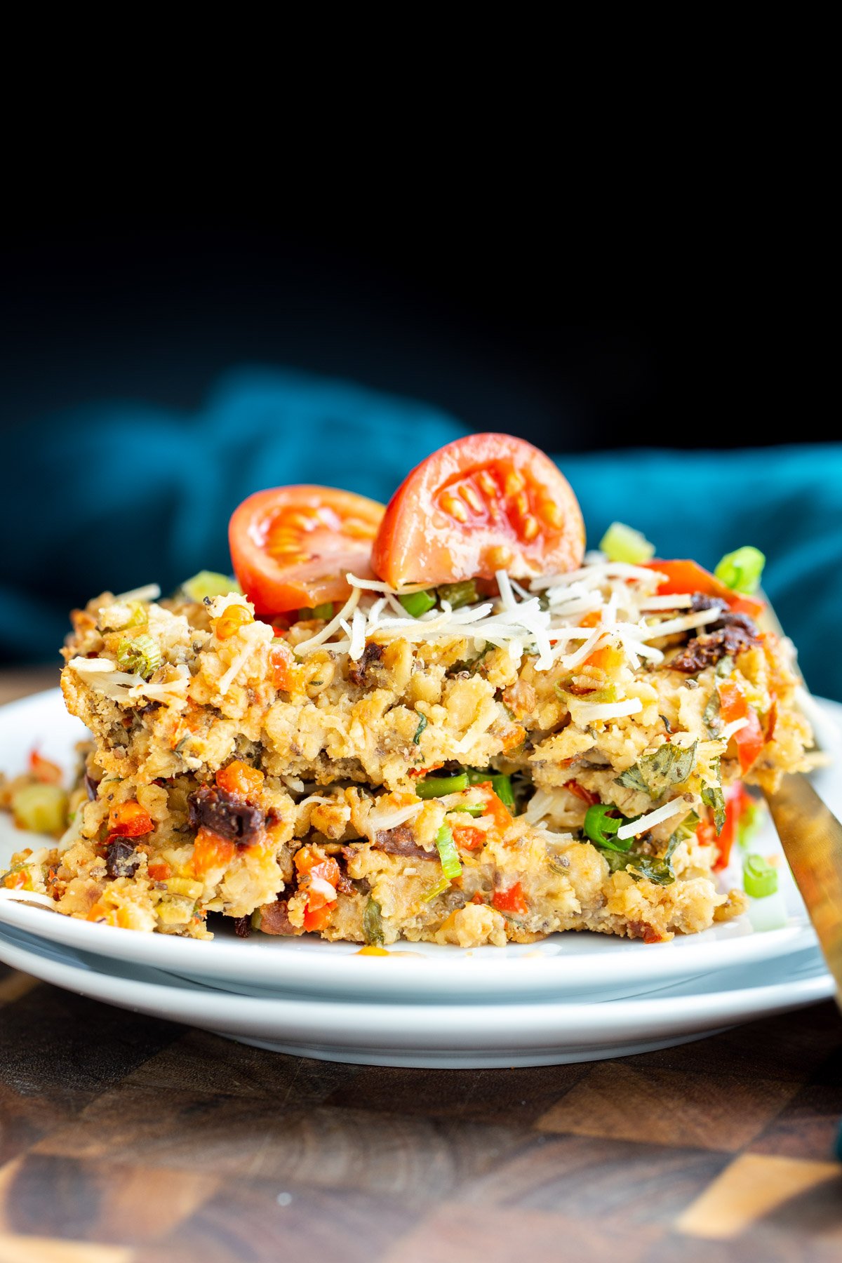 savory oatmeal bake  a slice of savory oatmeal bake topped with parmesan cheese and tomatoes
