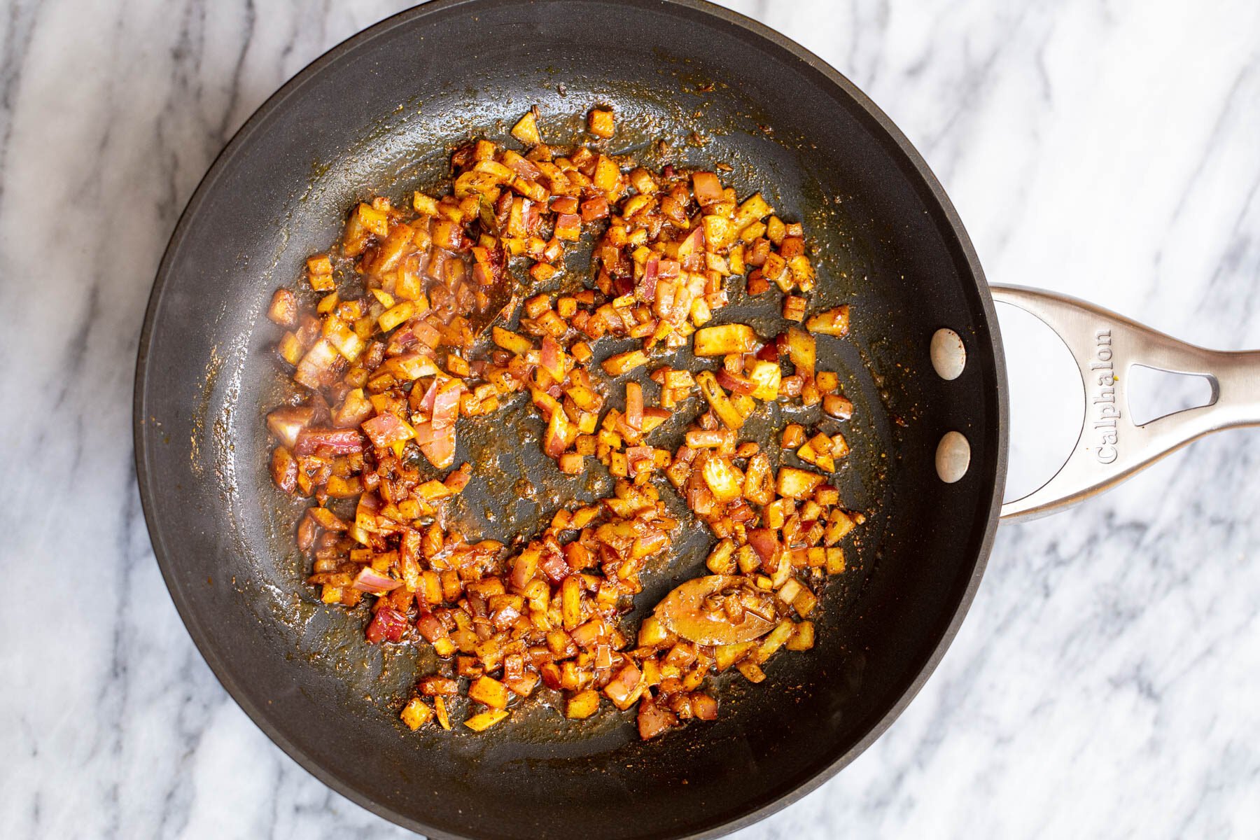 fried onion cubes with spices in a skillet