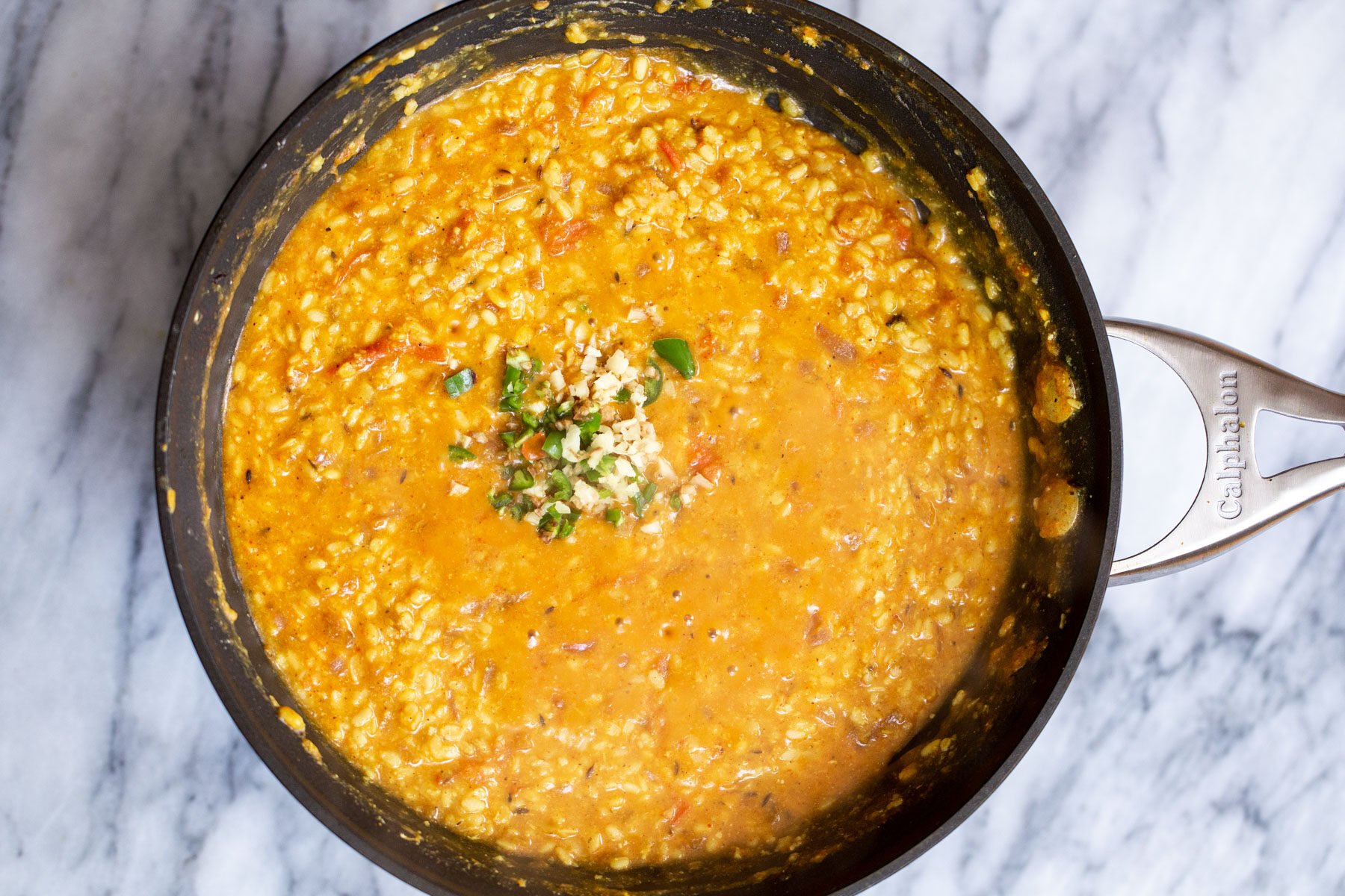 green chile and garlic being added to ural dal in a black skillet