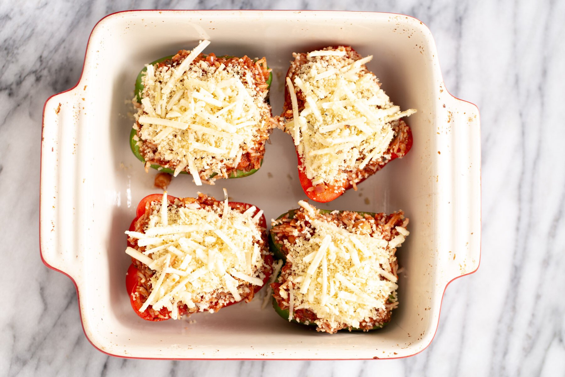 vegan stuffed bell pepper vegan stuffed bell peppers topped with cheese in a white casserole dish