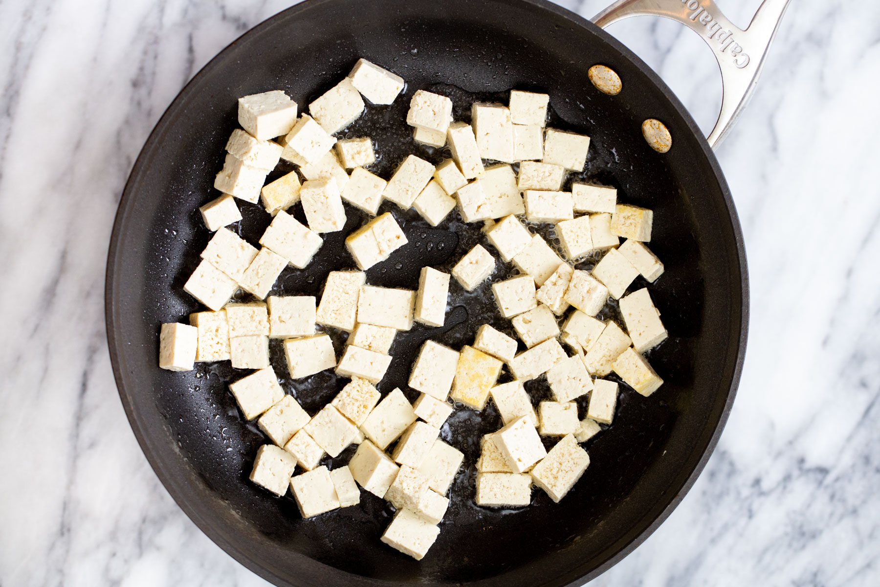 tofu cubes frying in a sauteeing pan
