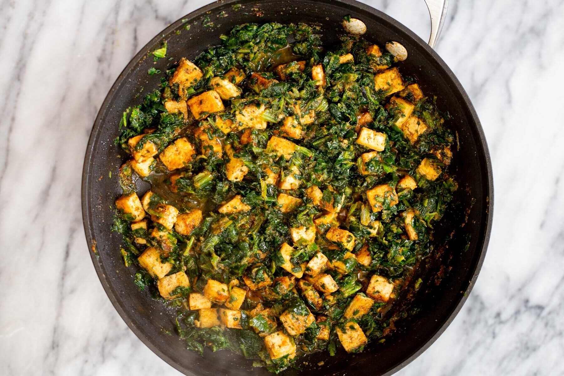 overhead shot of tofu cubes and spinach in a skillet