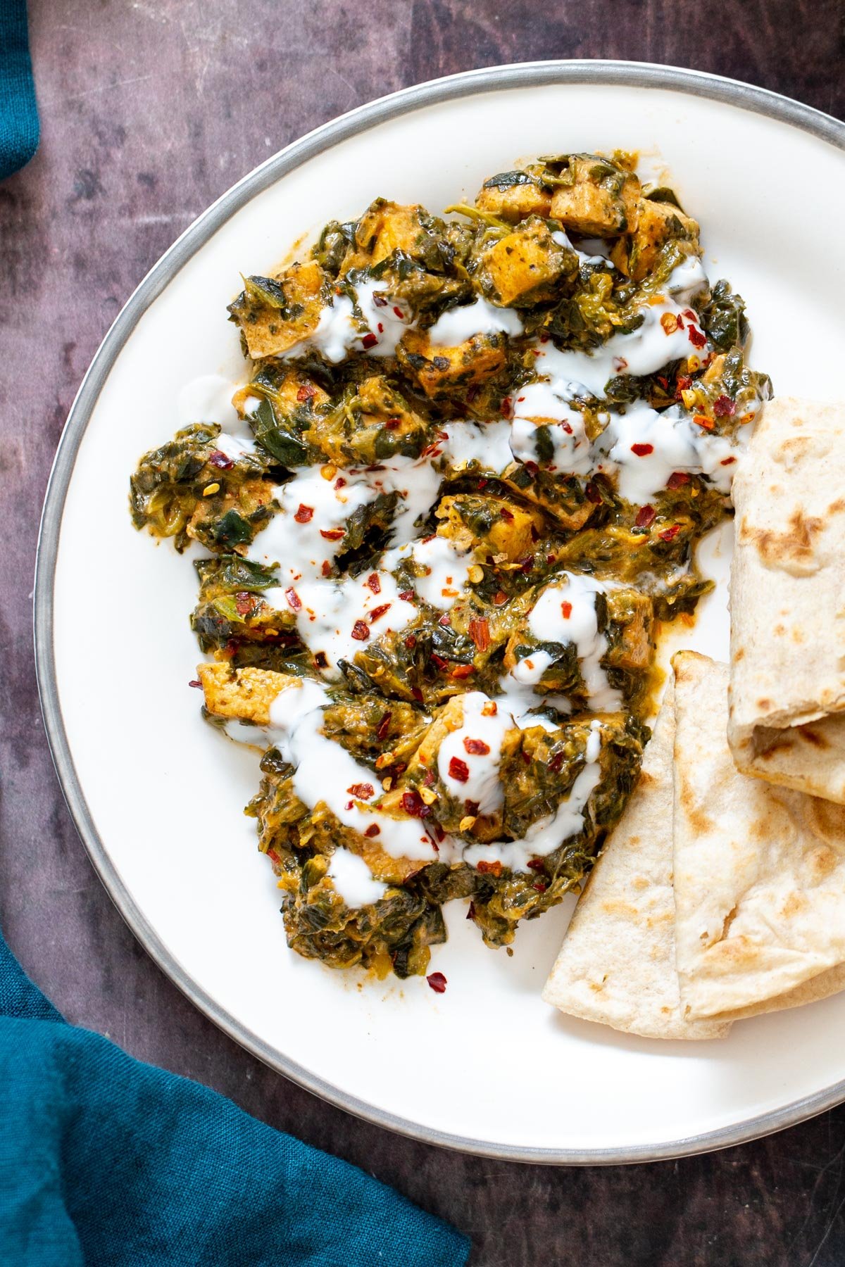 spinach tofu curry a serving of spinach tofu curry drizzled with yogurt and served with flatbread