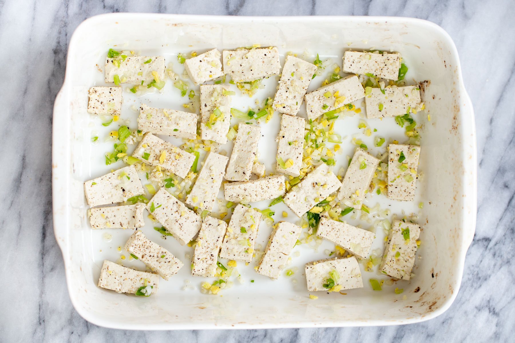 firm tofu cubes in a casserole dish along with garlic and ginger