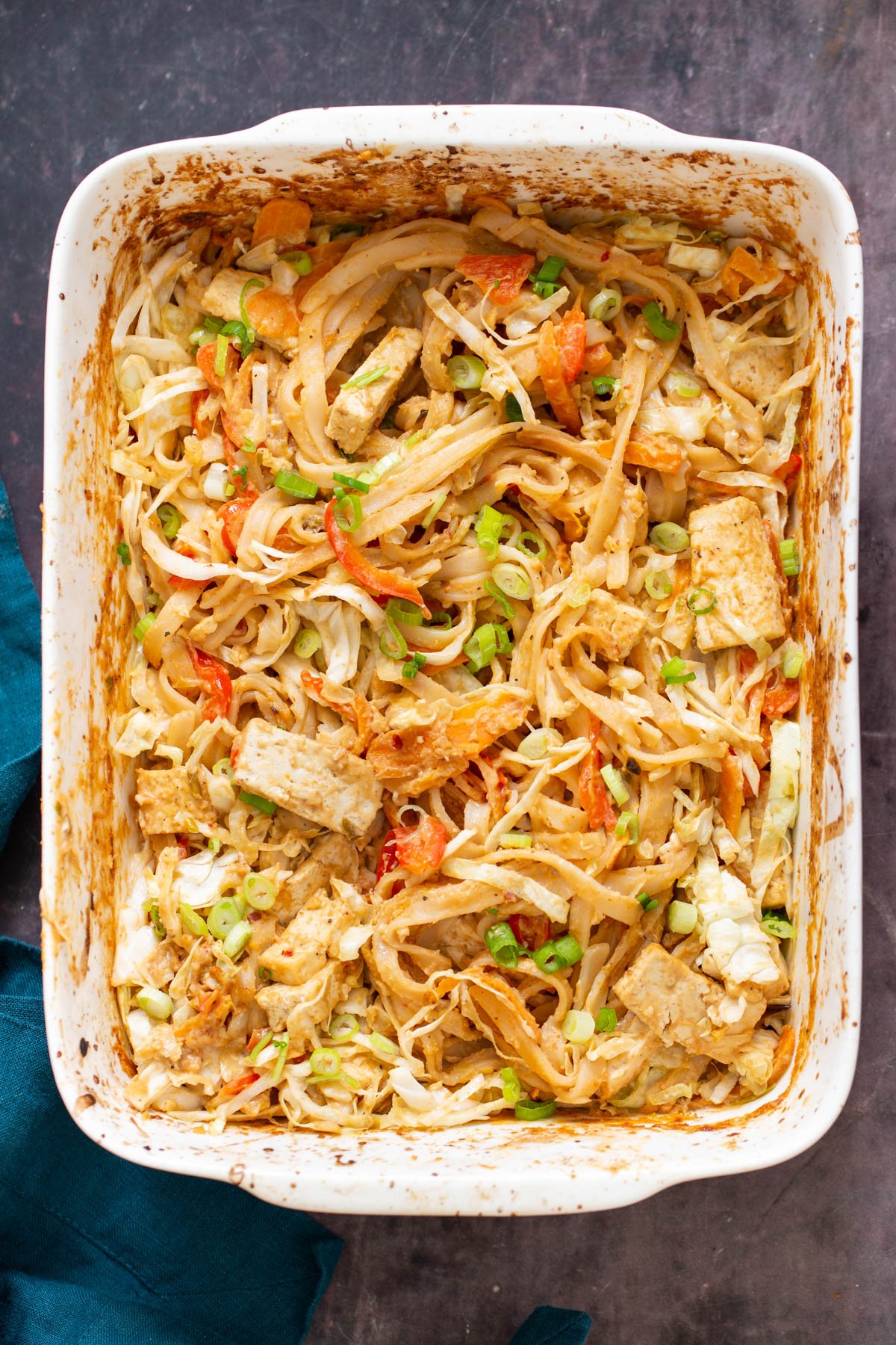 a white casserole dish with peanut butter rice noodles in a creamy sauce with veggies and tofu