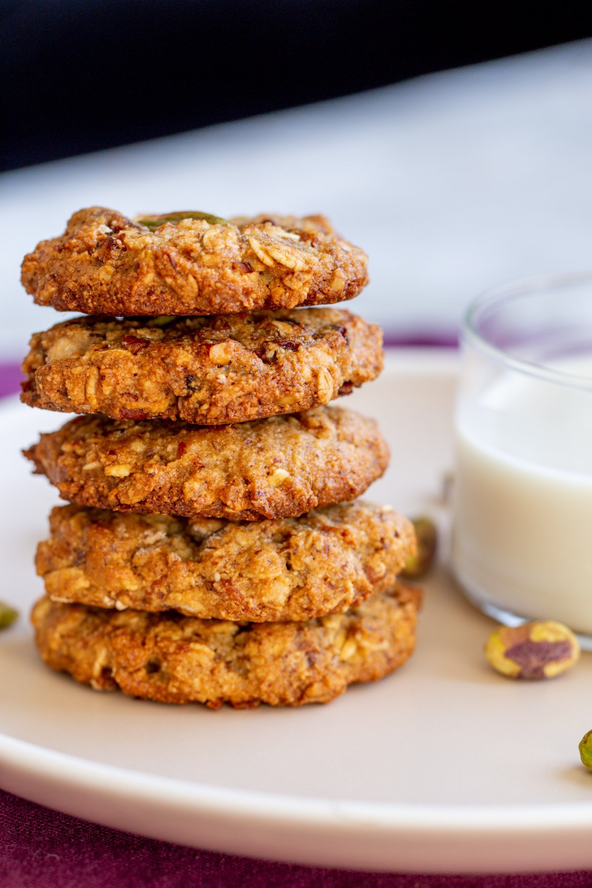 a stack of vegan carrot cake cookies with a glass of milk