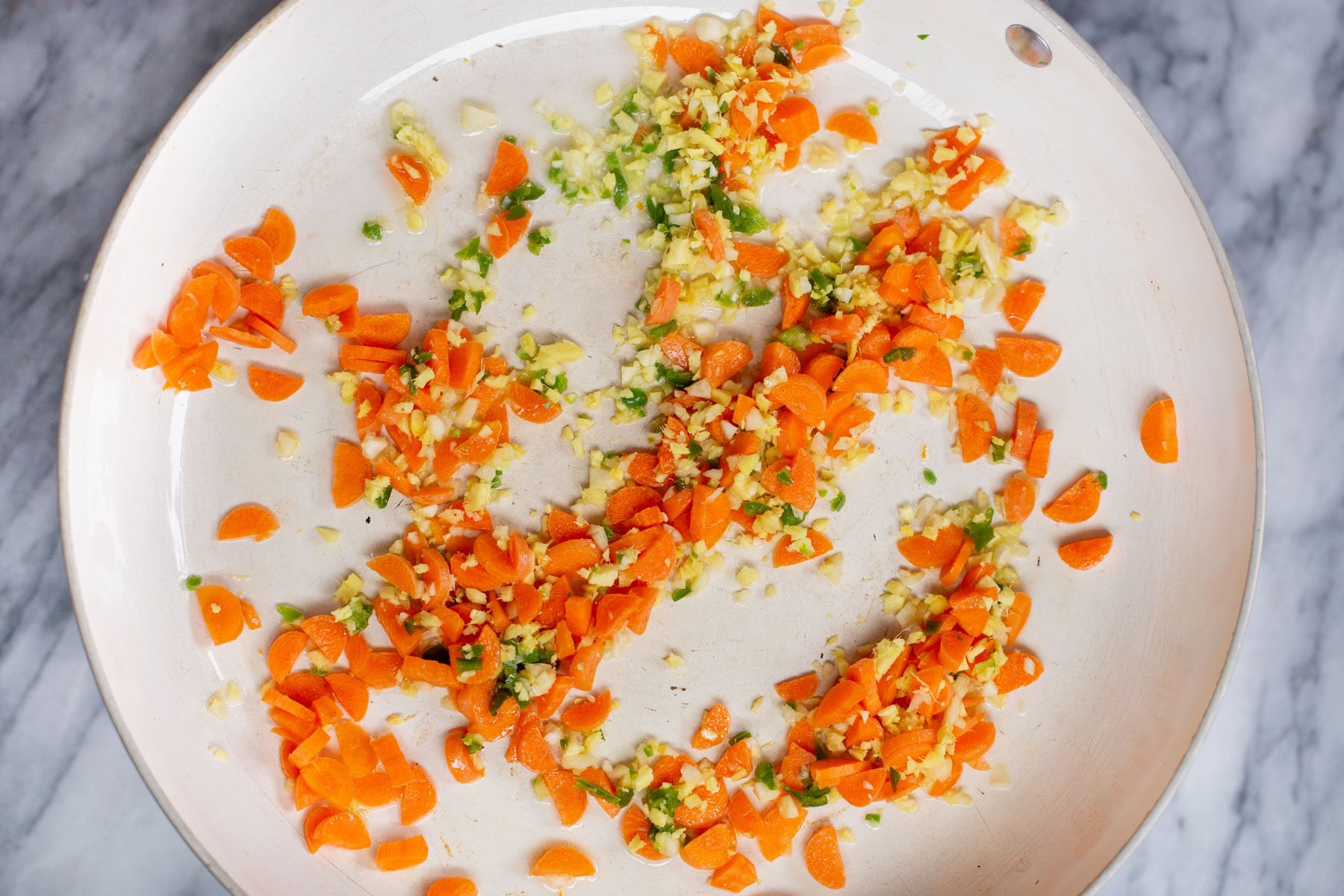 garlic, ginger and carrots in a sauteeing pan