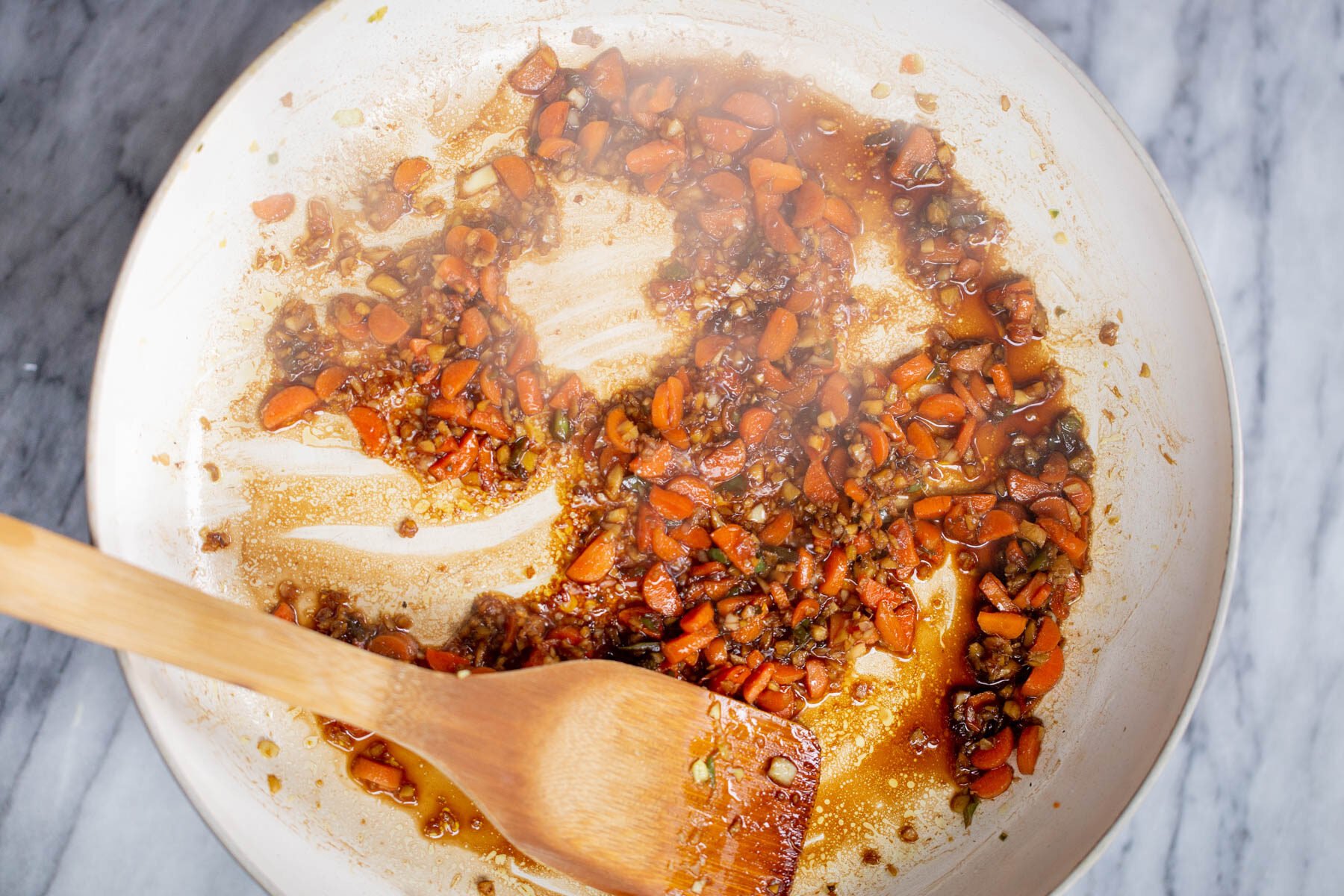 stirfy sauce being added to a pan with ginger and garlic