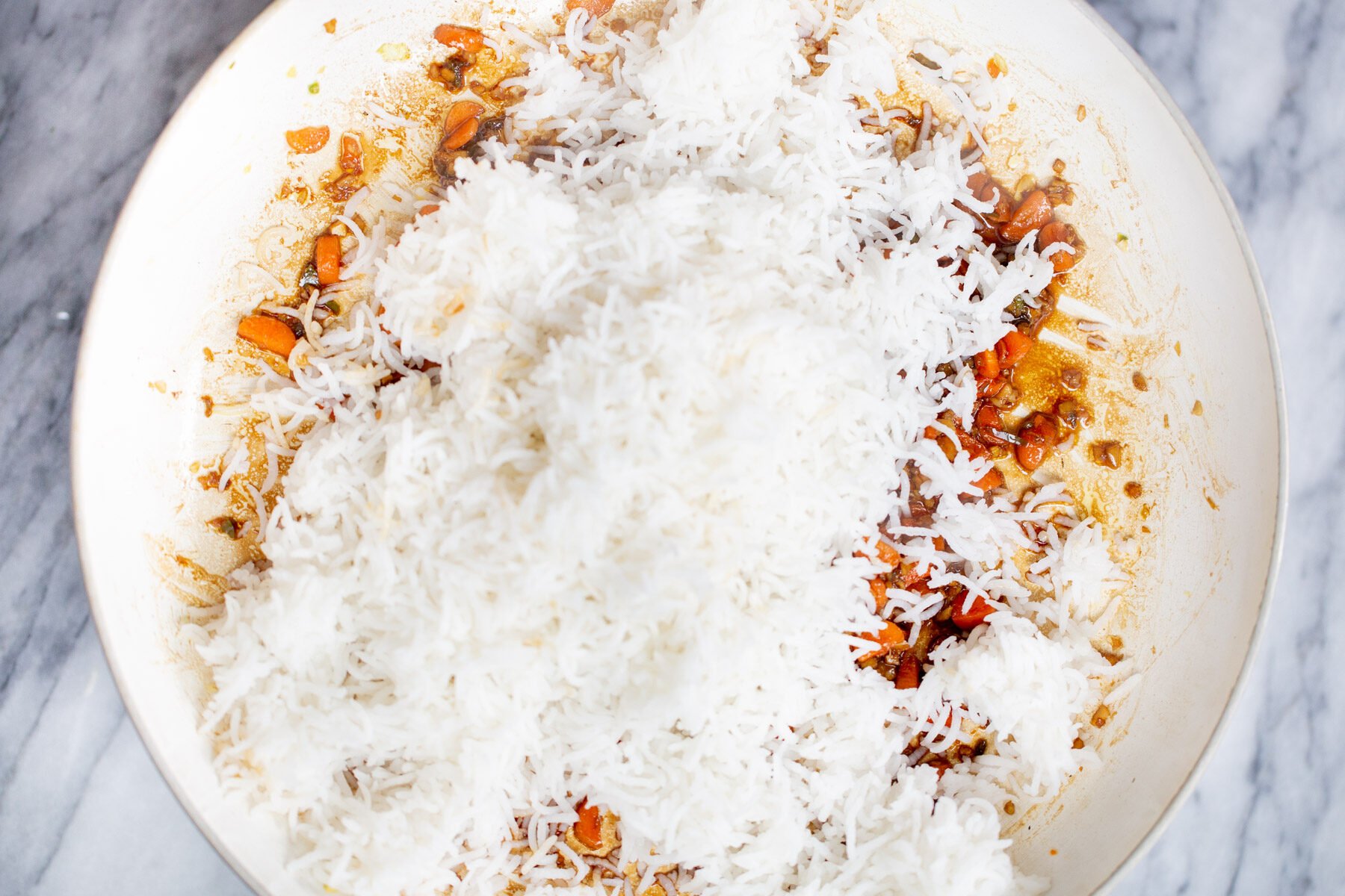 cooked rice being added to a pan to make Indo Chinese fried rice