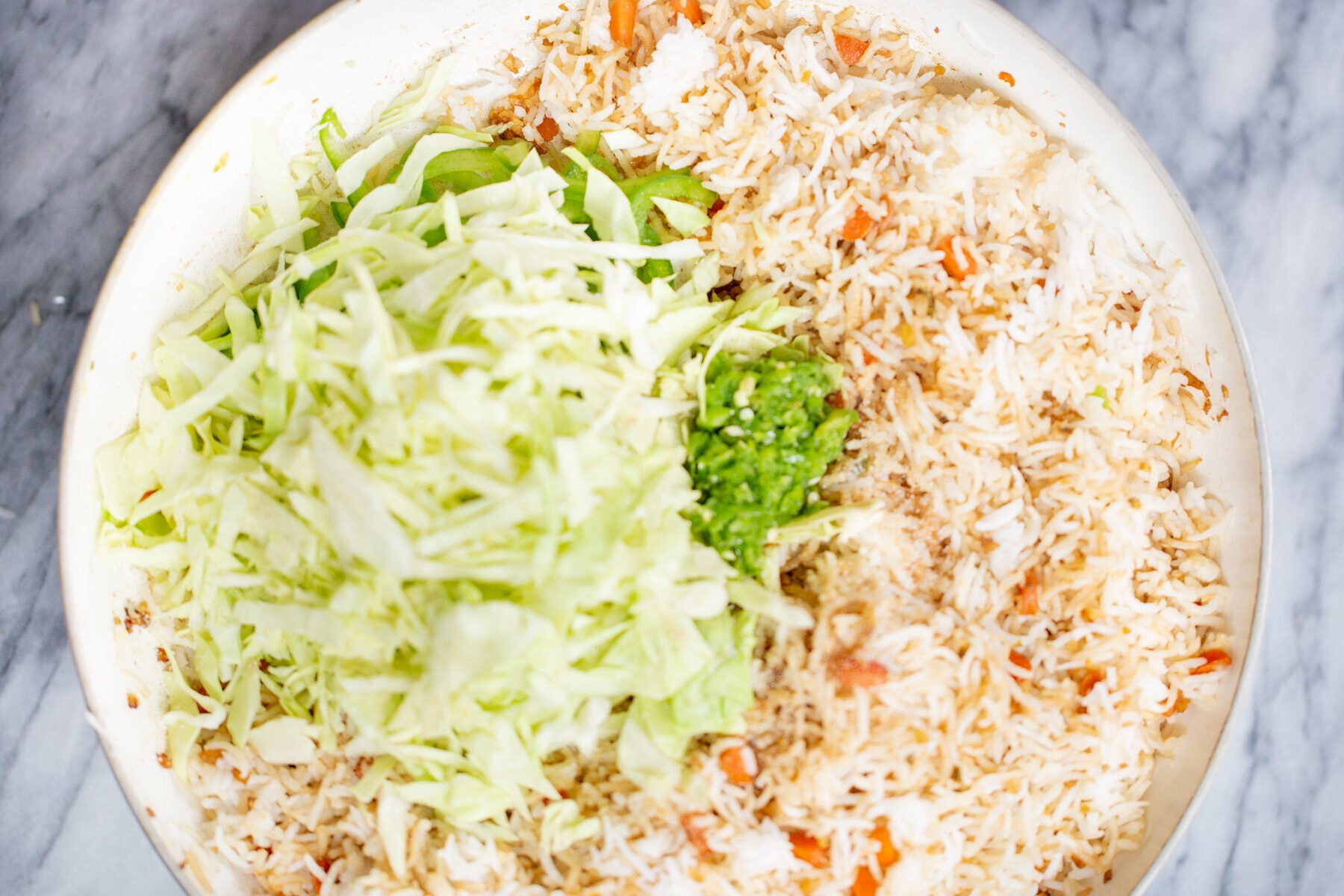 shredded cabbage being added to a pan with fried rice