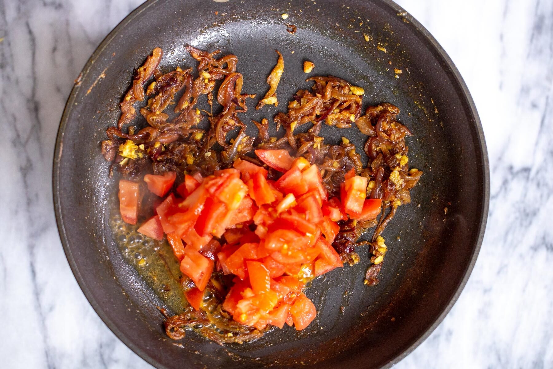 fresh tomatoes being added to sauteeing pan