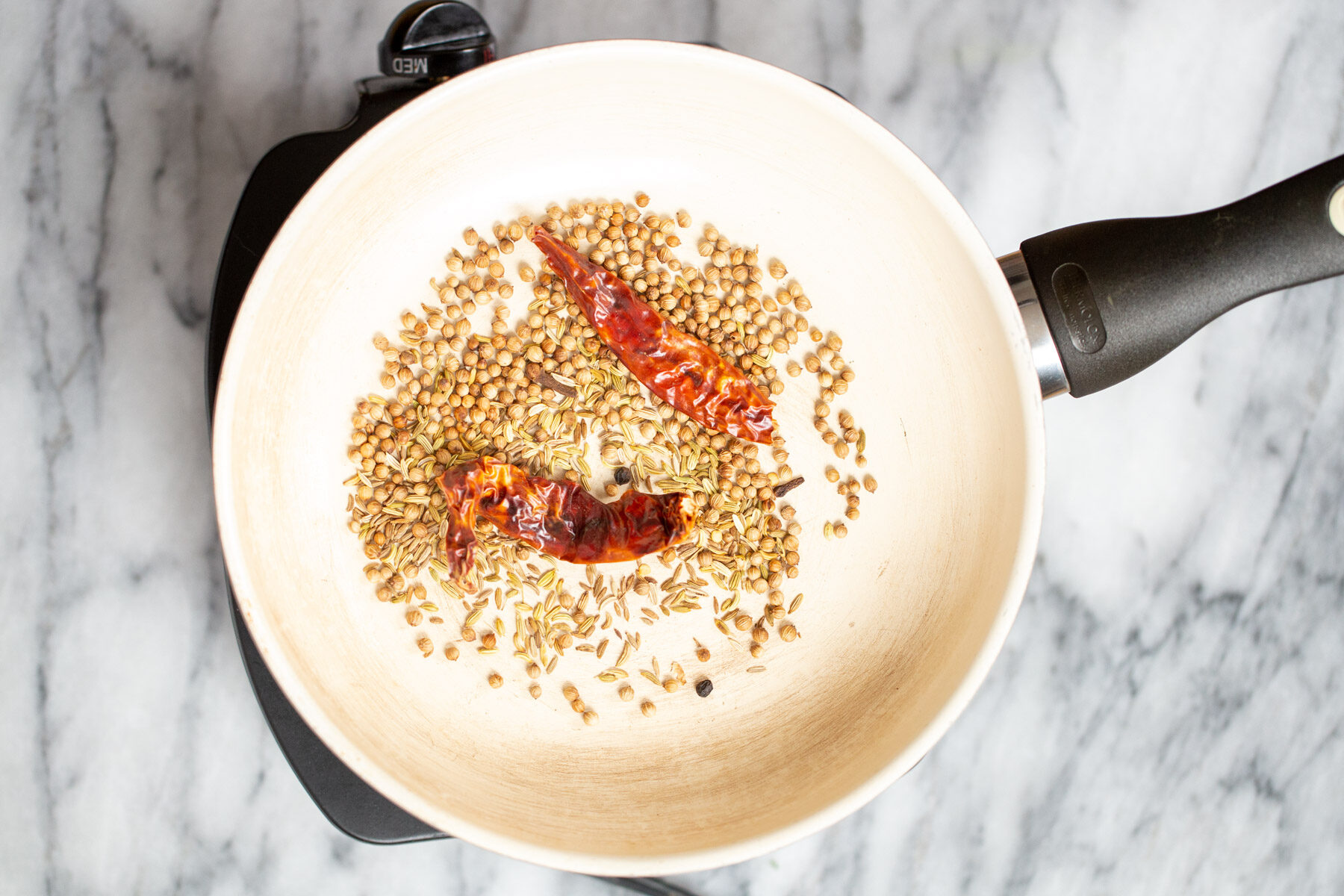 whole spiced being toasted in a pan