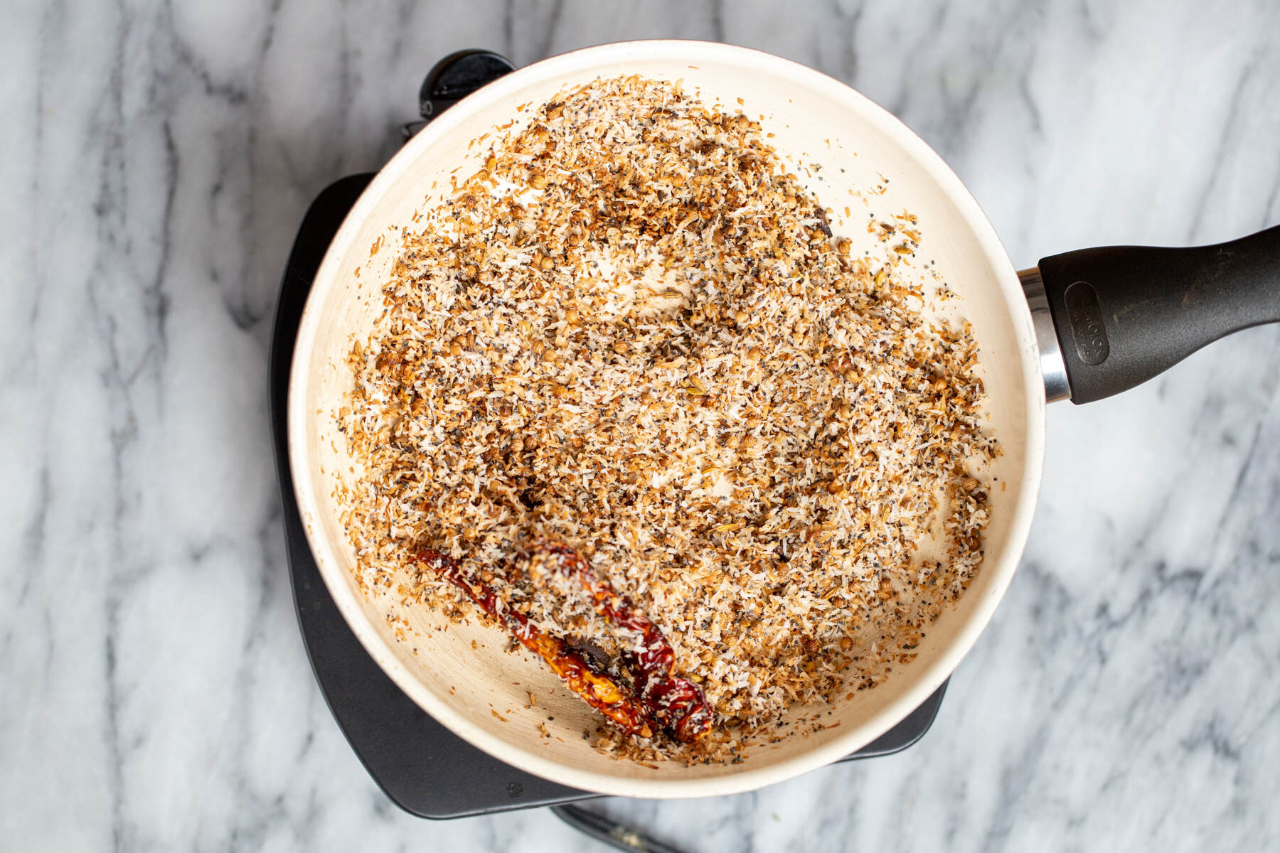 shredded coconut being toasted in a pan along with spices