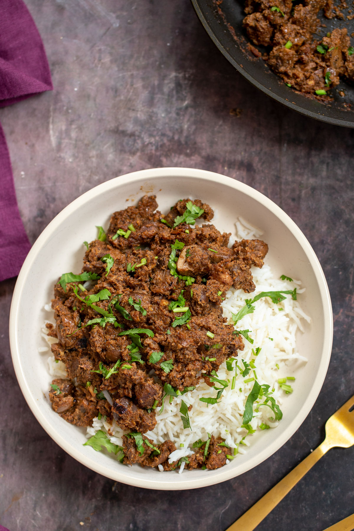 a serving of vegan mushroom xacuti with rice in a white bowl