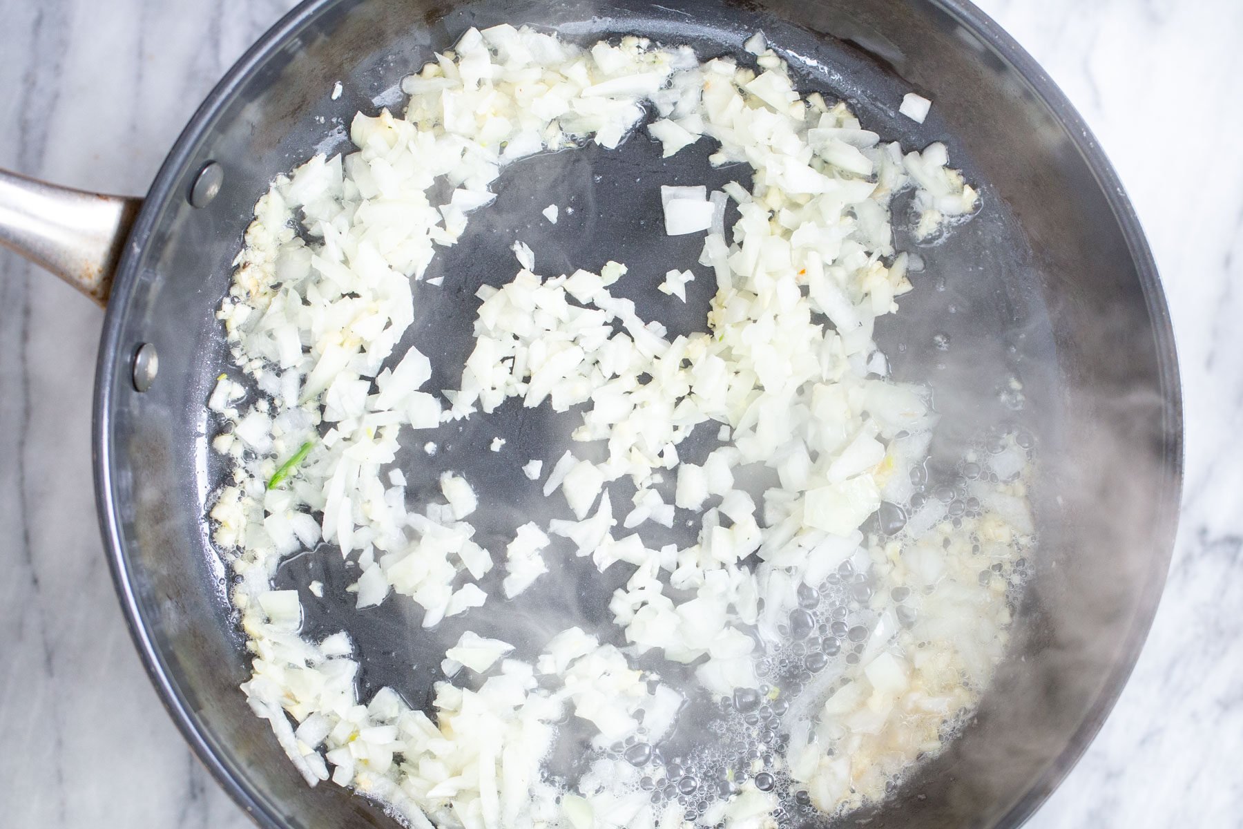 minced onion being sauteed in a skillet
