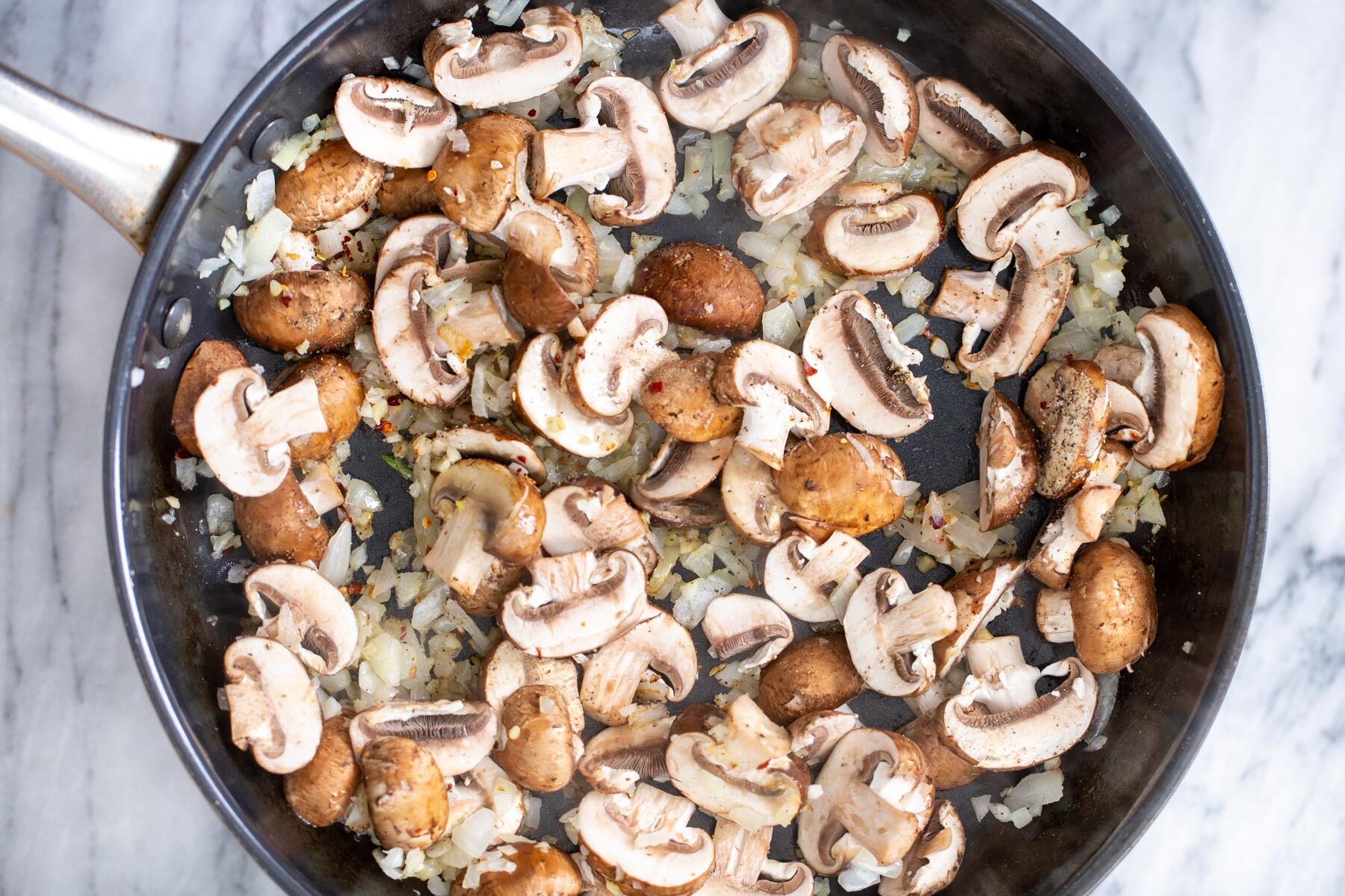 sliced baby bella mushrooms cooked in a sauteeing pan