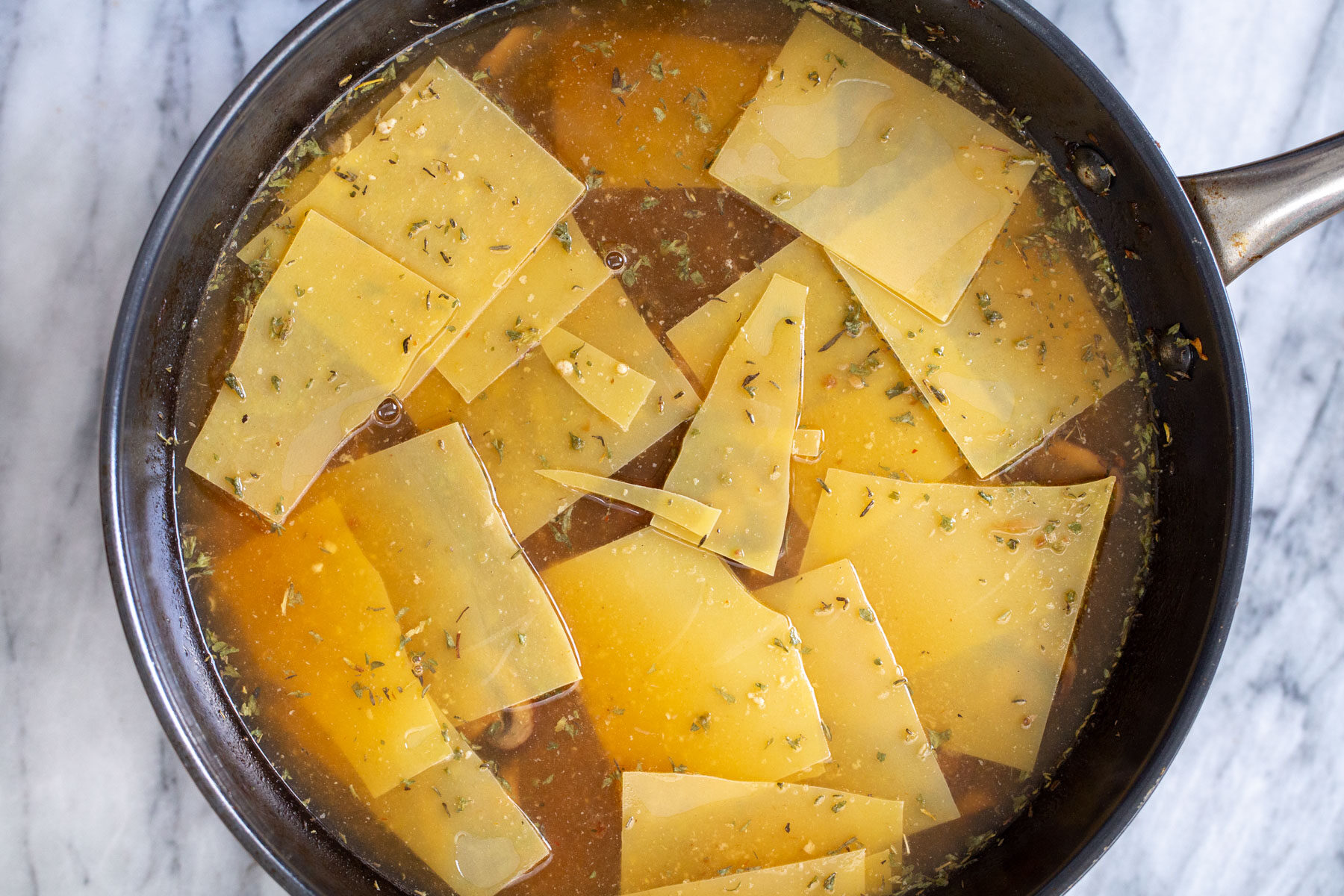 broken pasta noodles cooking in a black skillet