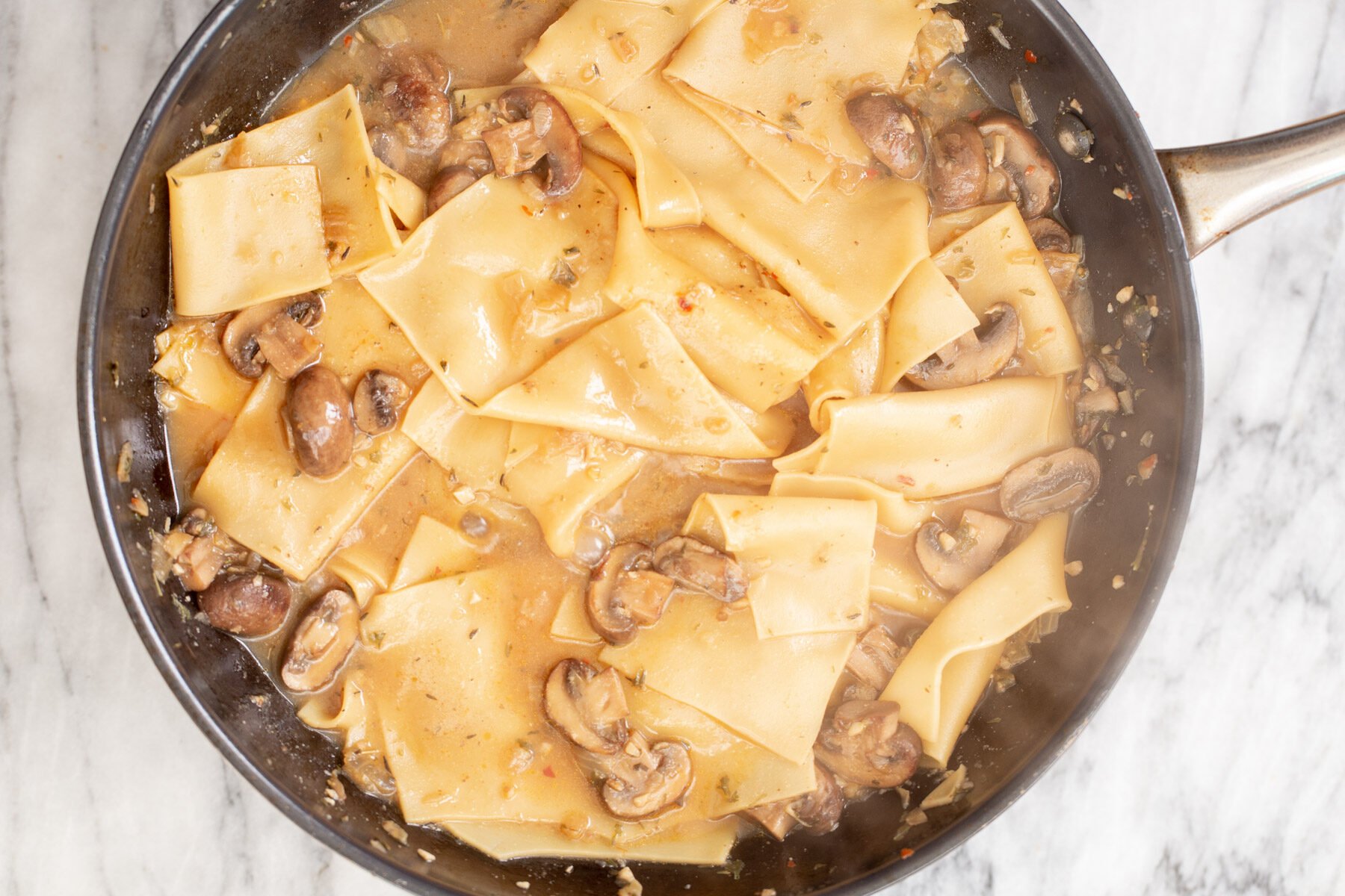 mushroom gravy and cooked broken lasagna noodles in a skillet