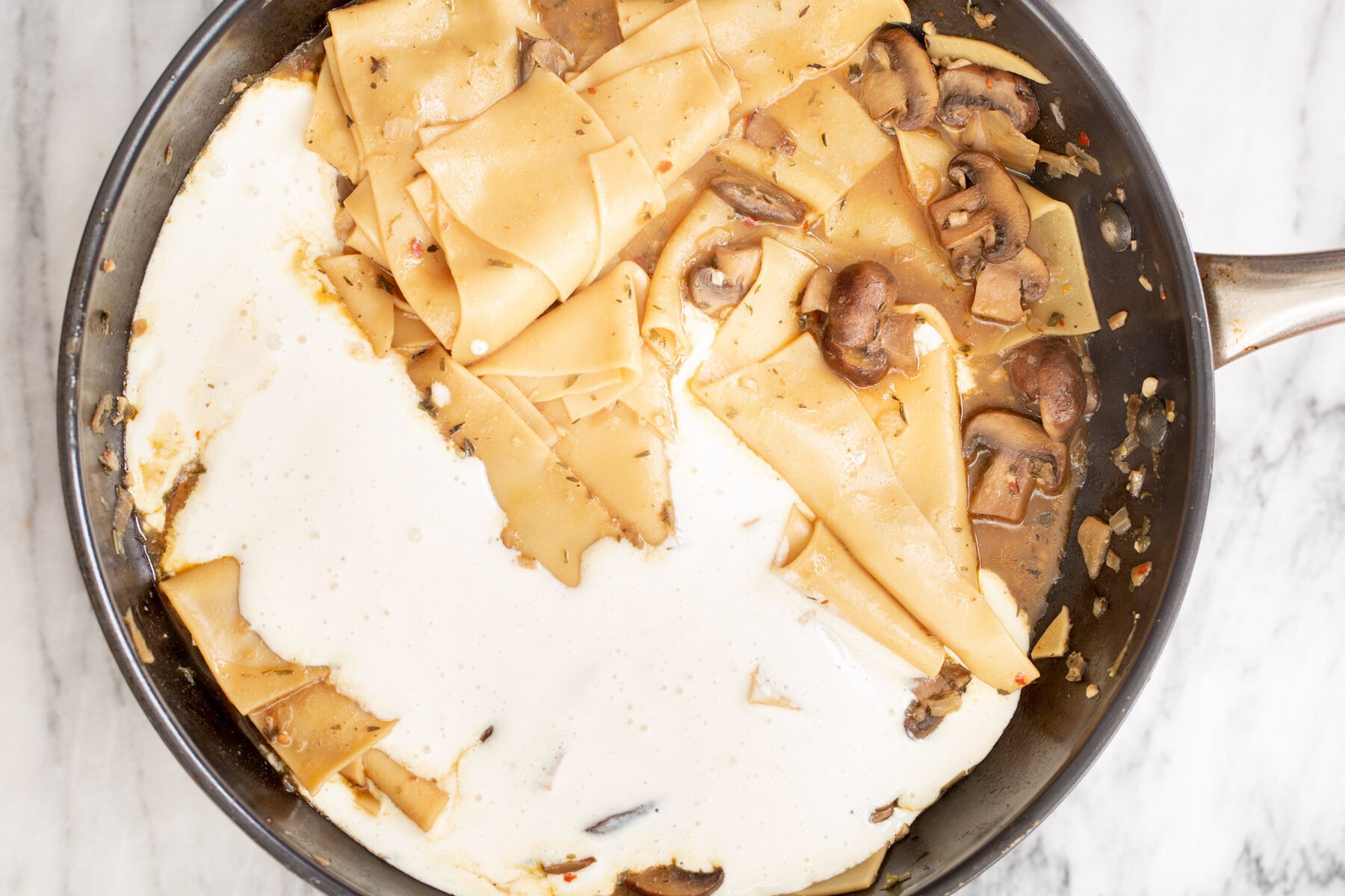 dairyfree vegan tofu bechamel being added to skillet with mushroom pasta