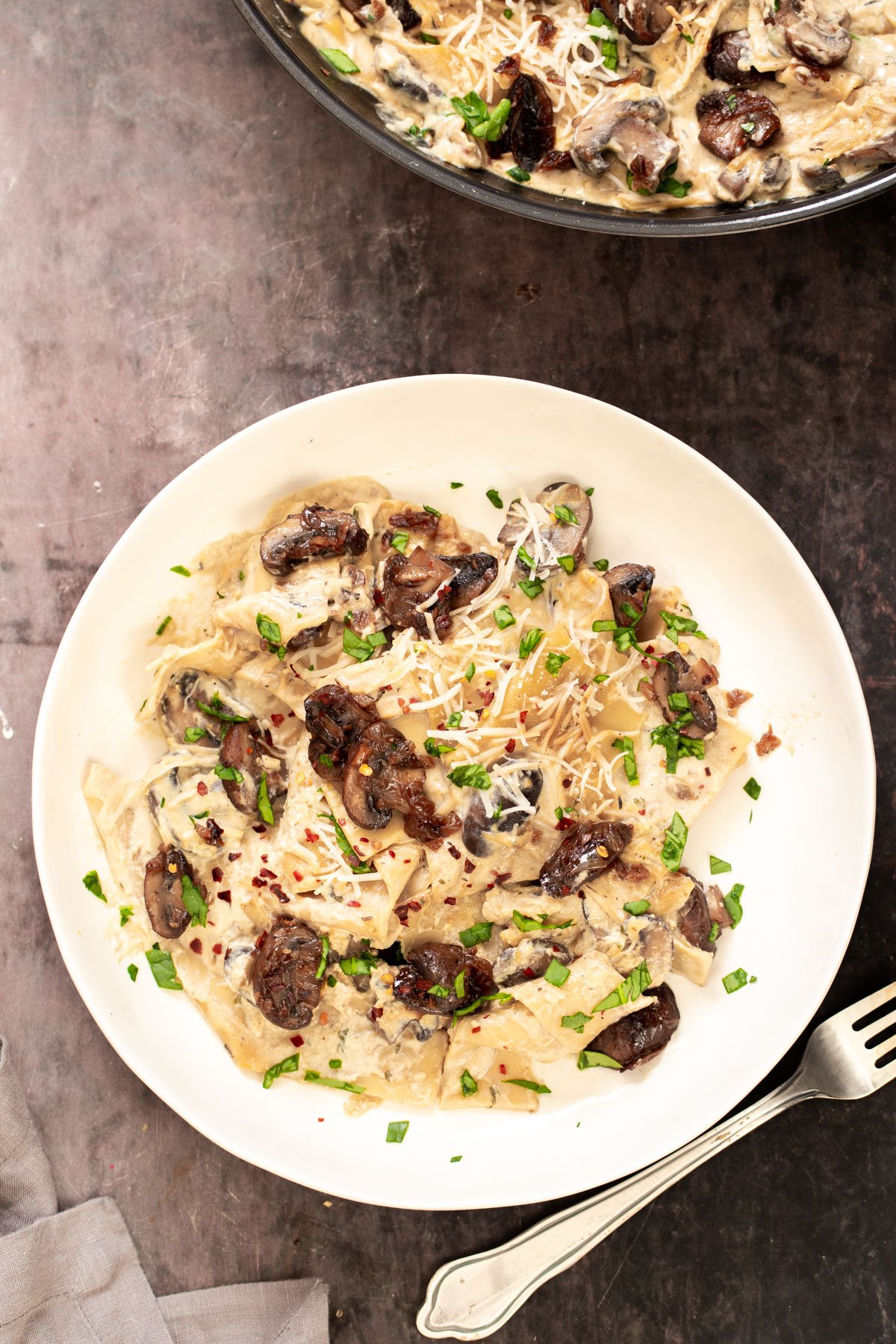 a plate with vegan skillet lasagna topped with balsamic mushrooms and vegan parmesan cheese