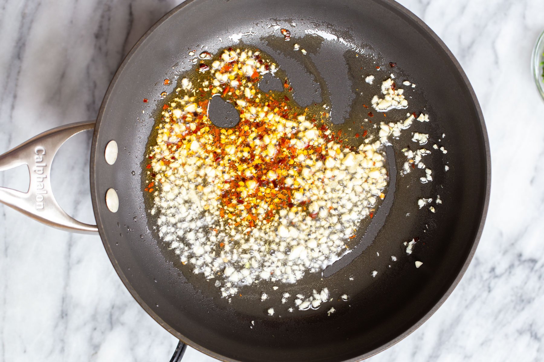 minced garlic and red pepper flakes frying in a pan