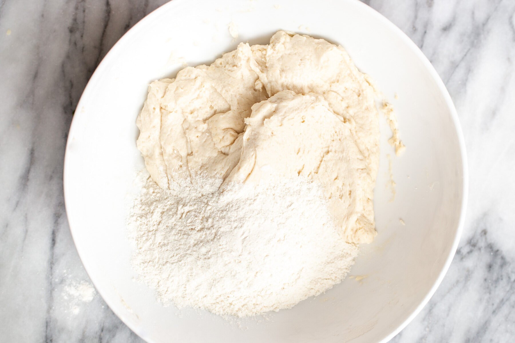 vegan naan bread dough being prepared in a white bowl
