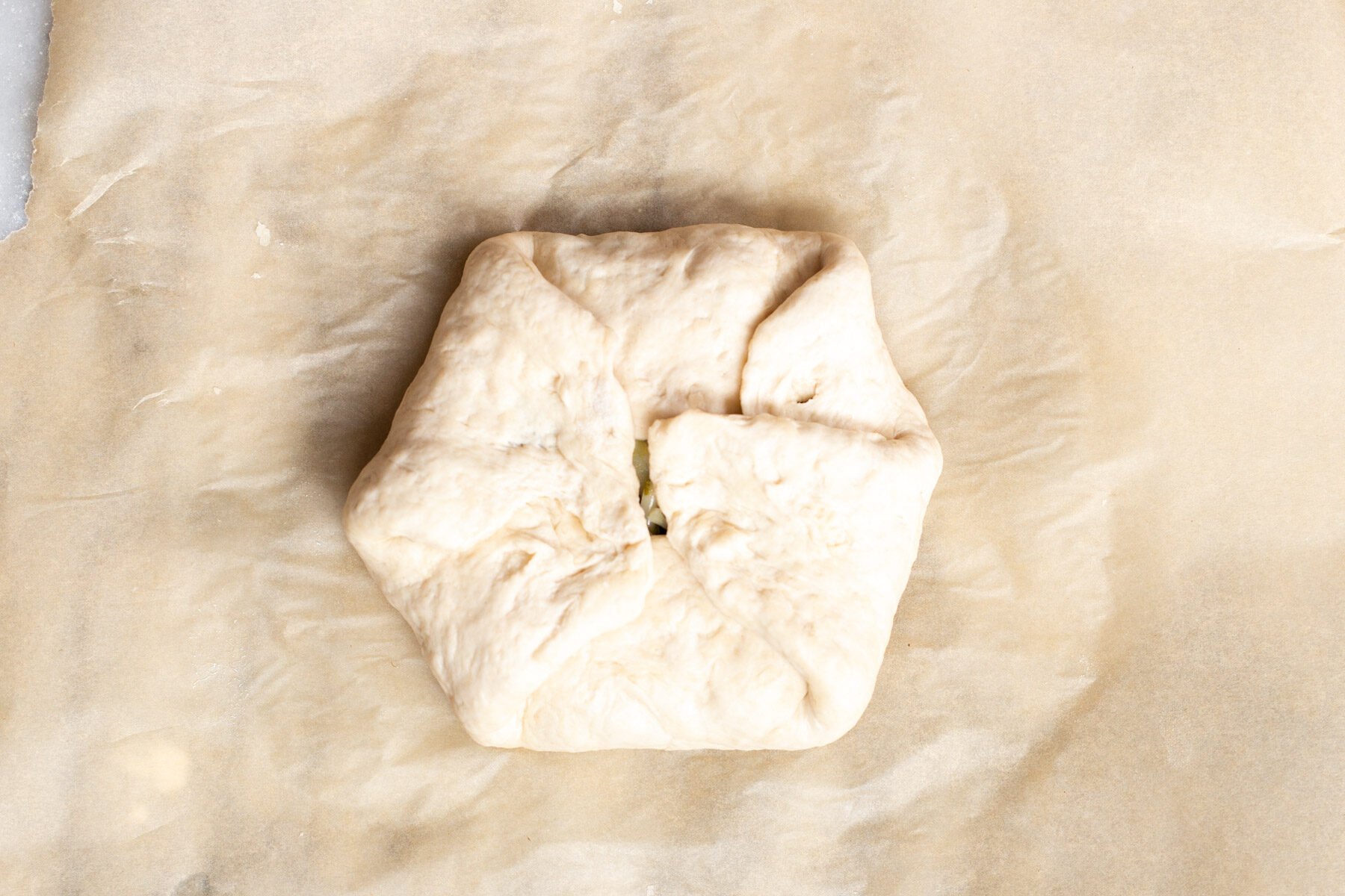 edges being folded over the spinach and cheese filling for making a vegan naan bread