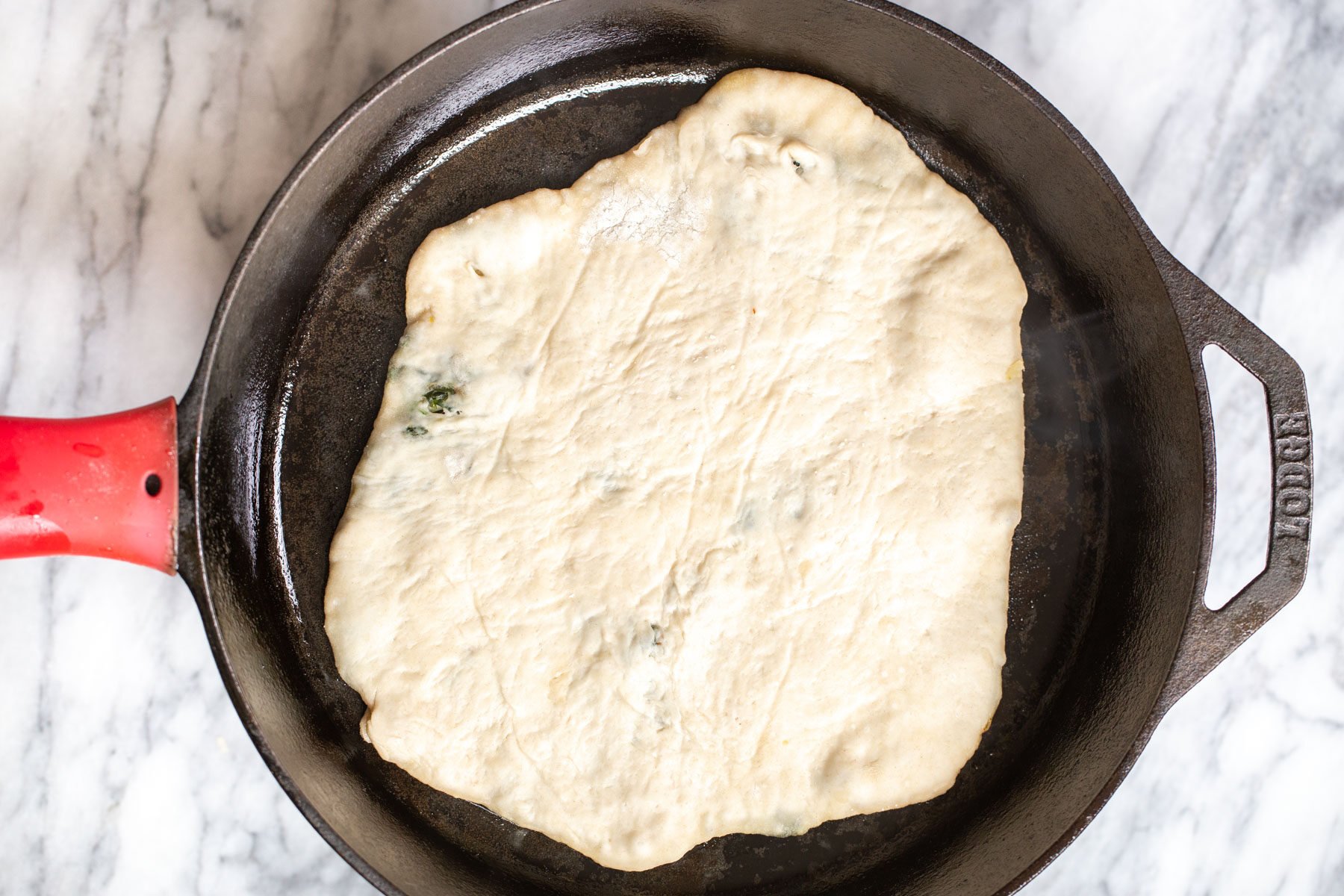 stuffed spinach naan being added to a skillet