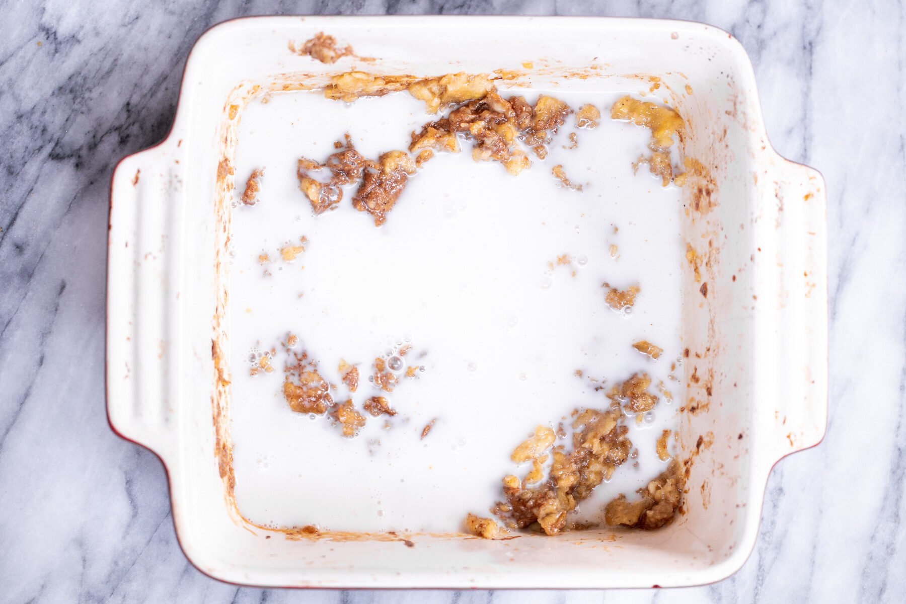 milk being added to roasted banana puree in casserole dish