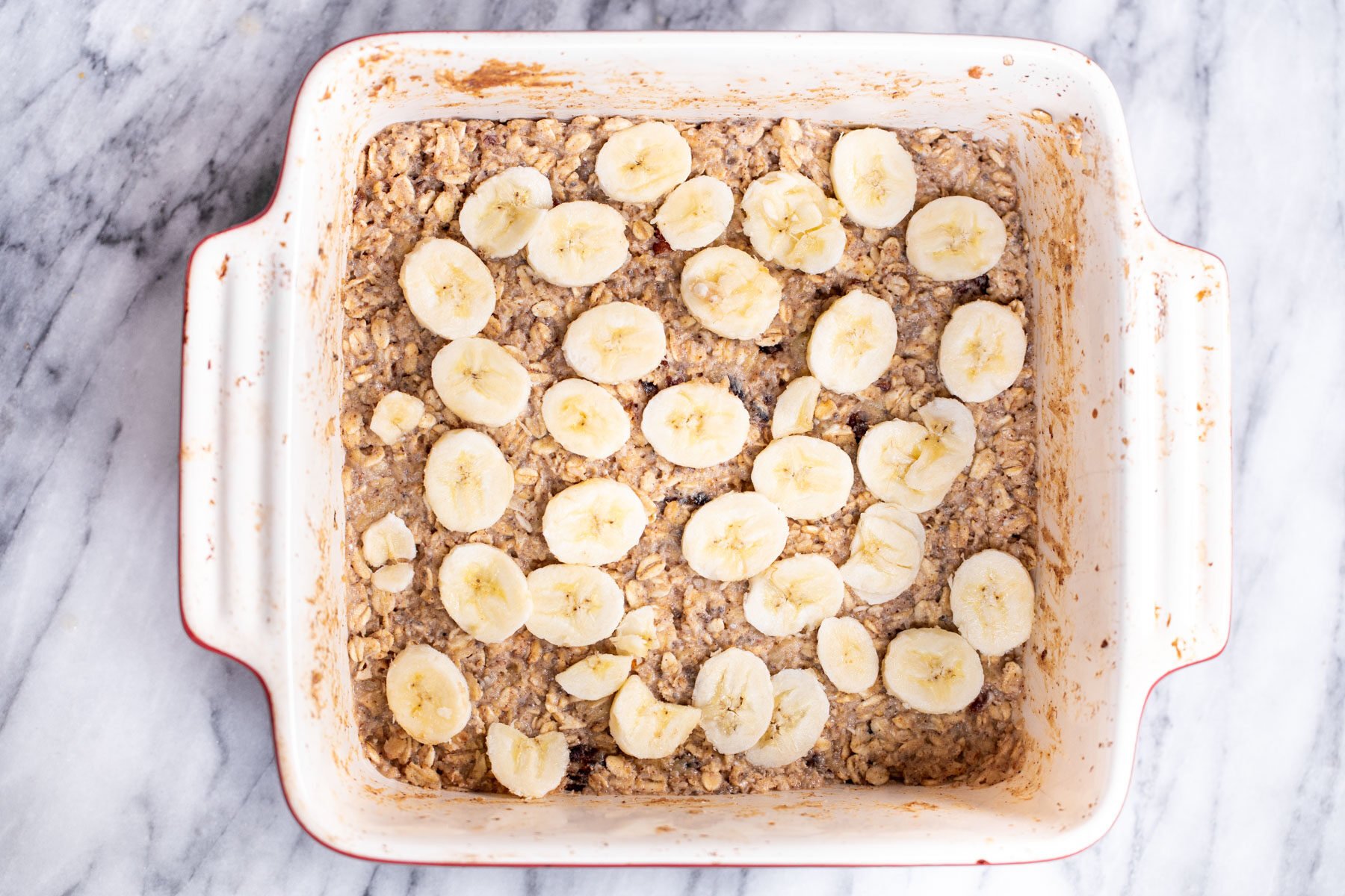 banana oatmeal bars being topped with sliced bananas