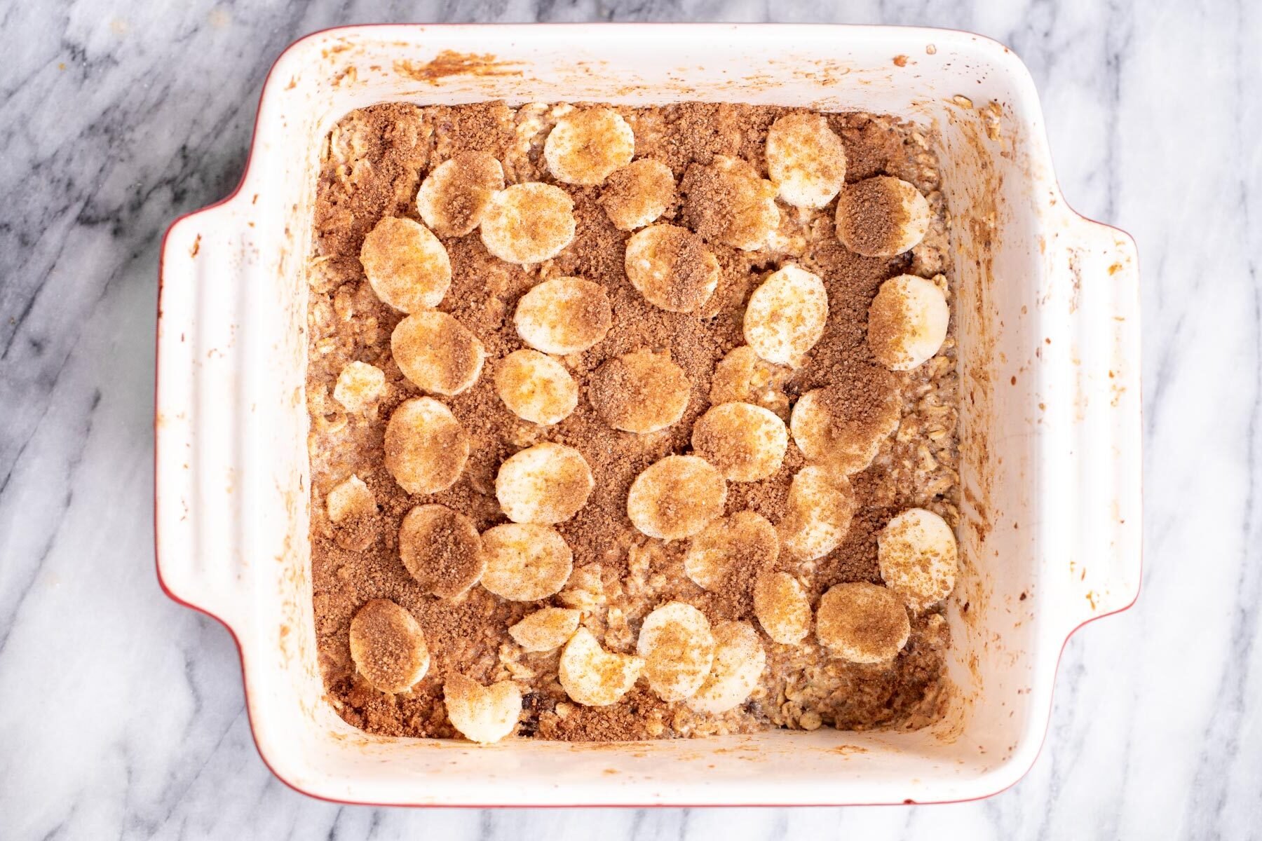 coconut sugar cinnamon streusel being sprinkled on top of banana oatmeal bars